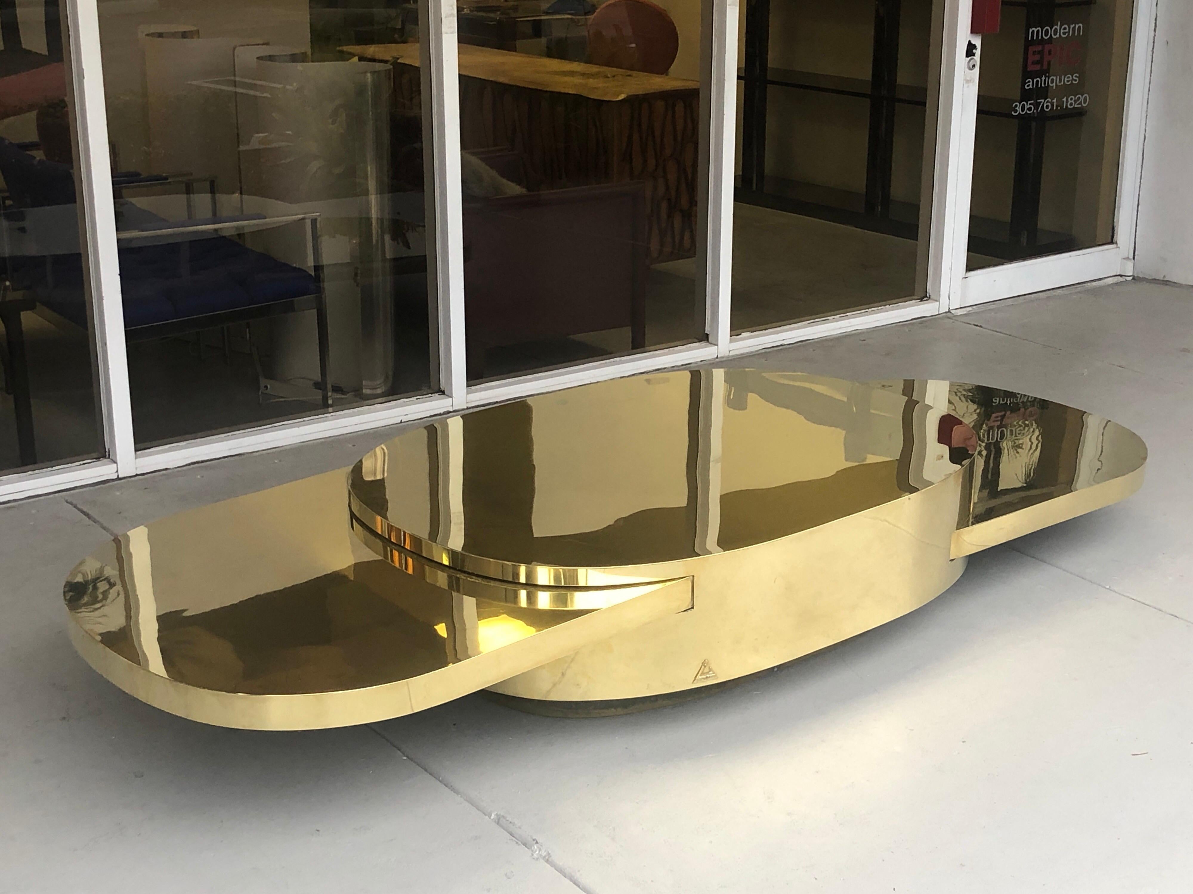 An Ellisse brass coffee table by Gabriella Cespi. From her celebrated and iconic Plurimi series. Oval brass shape with 2 retractable elliptical tops in brass as well. Extends from 51