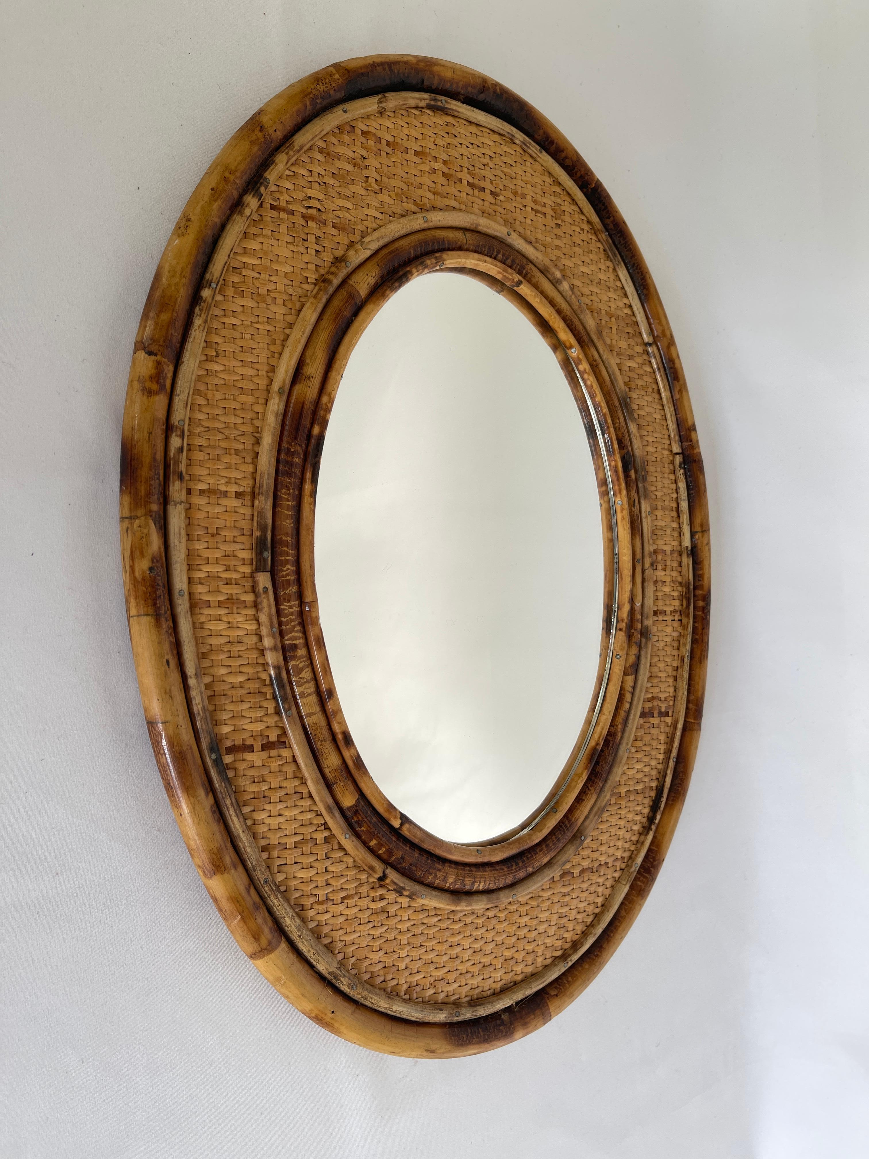 1970's Oval bamboo framed rattan mirror. Wonderful rich color, graciously curved. and finely crafted.