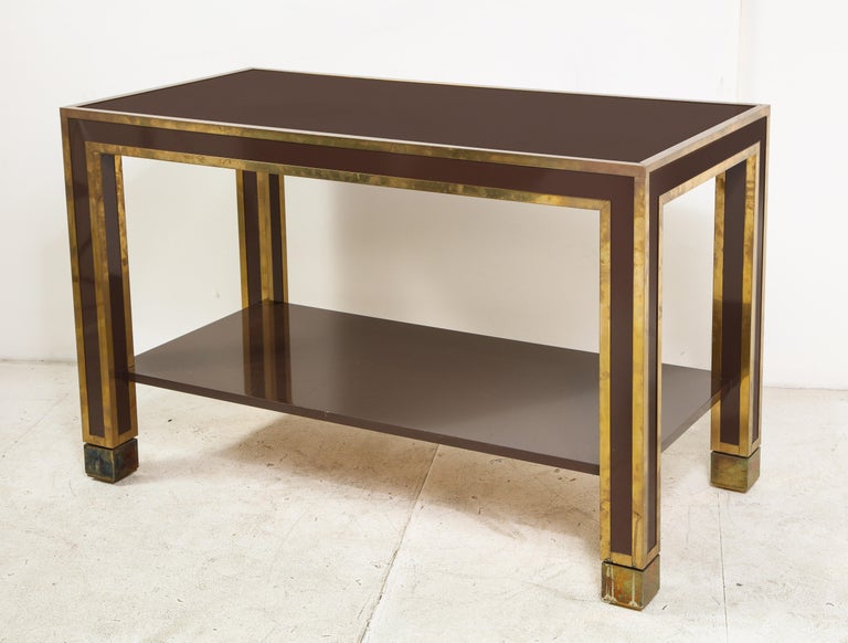 Italian 1960s brown lacquer and brass inlaid two-tier table. Has floor adjusters on each leg for leveling.
