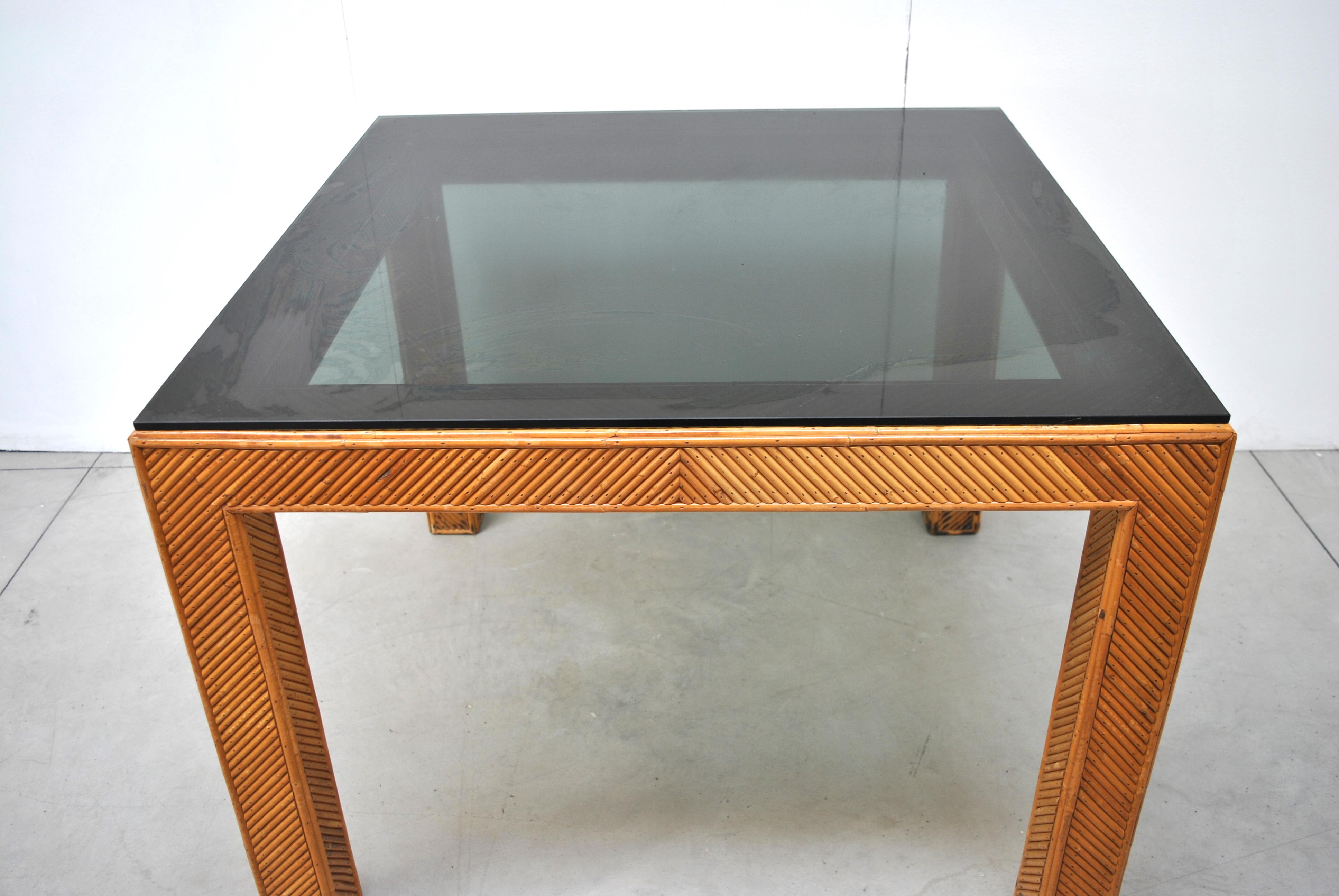 Table italienne en rotin, début des années 1970, avec plateau en verre fumé.