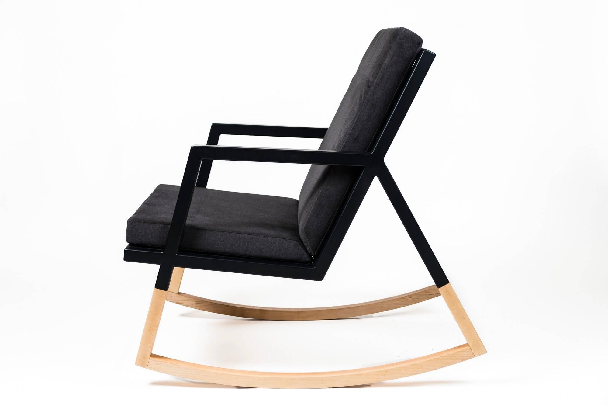 Le fauteuil à bascule moderne Gabriella est fabriqué à la main sur commande à partir de notre conception unique de cadre en tubes d'acier texturé noir Ambrozia, avec un dossier en lattes de bois massif et une bascule en bois sans soudure. Ce
