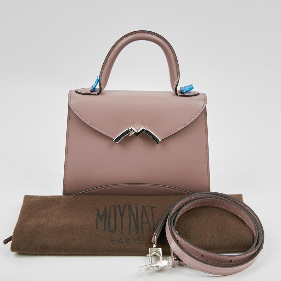 Gabrielle mini bag from Maison MOYNAT. It is calfskin carat powder. It is carried by a small handle or shoulder with its removable shoulder strap. The clasp which in the shape of a V pivots to allow the opening of the bag revealing an M like MOYNAT.