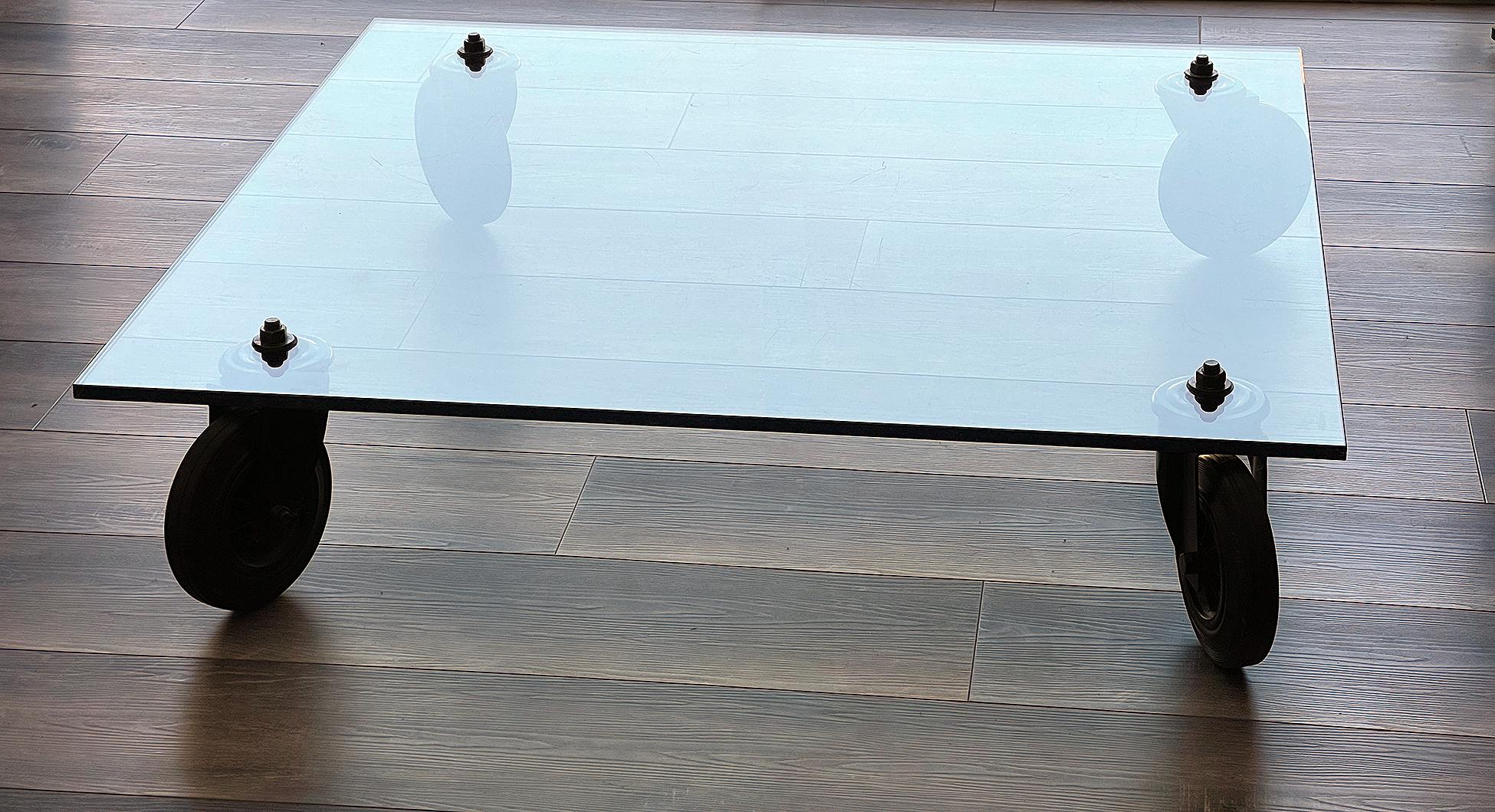 Table basse en verre de Gae Aulenti pour Fontana Arte avec roues en caoutchouc laqué noir.
Plateau en cristal épais monté sur quatre roues en fer laqué noir et caoutchouc.

Dimensions : 43