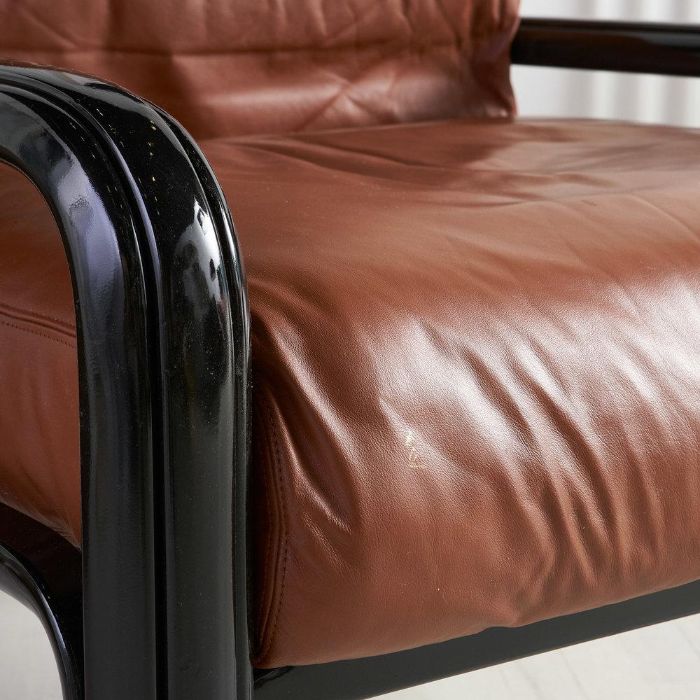 A fantastic pair of mod lounge chairs designed by Gae Aulenti for Knoll. Original upholstery in a rich caramel brown leather with newly lacquered black frames. 

Dimensions: 32