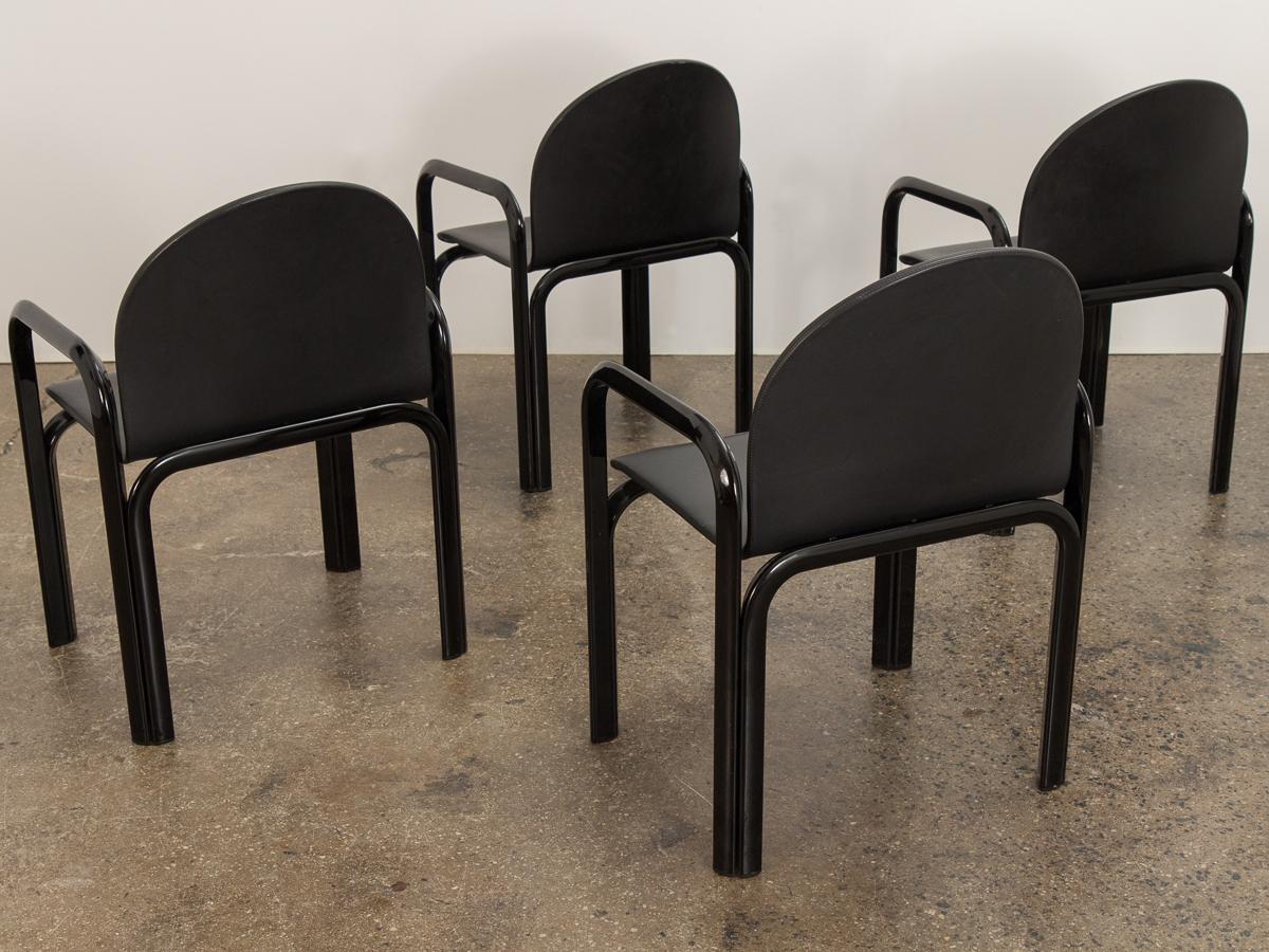 Set of four Italian Postmodern Orsay dining armchairs in black leather, designed by Gae Aulenti for Knoll. Round silhouette has super sleek vibes. Sturdy lacquered steel frame supports the padded seat for a comfortable seating experience. Original