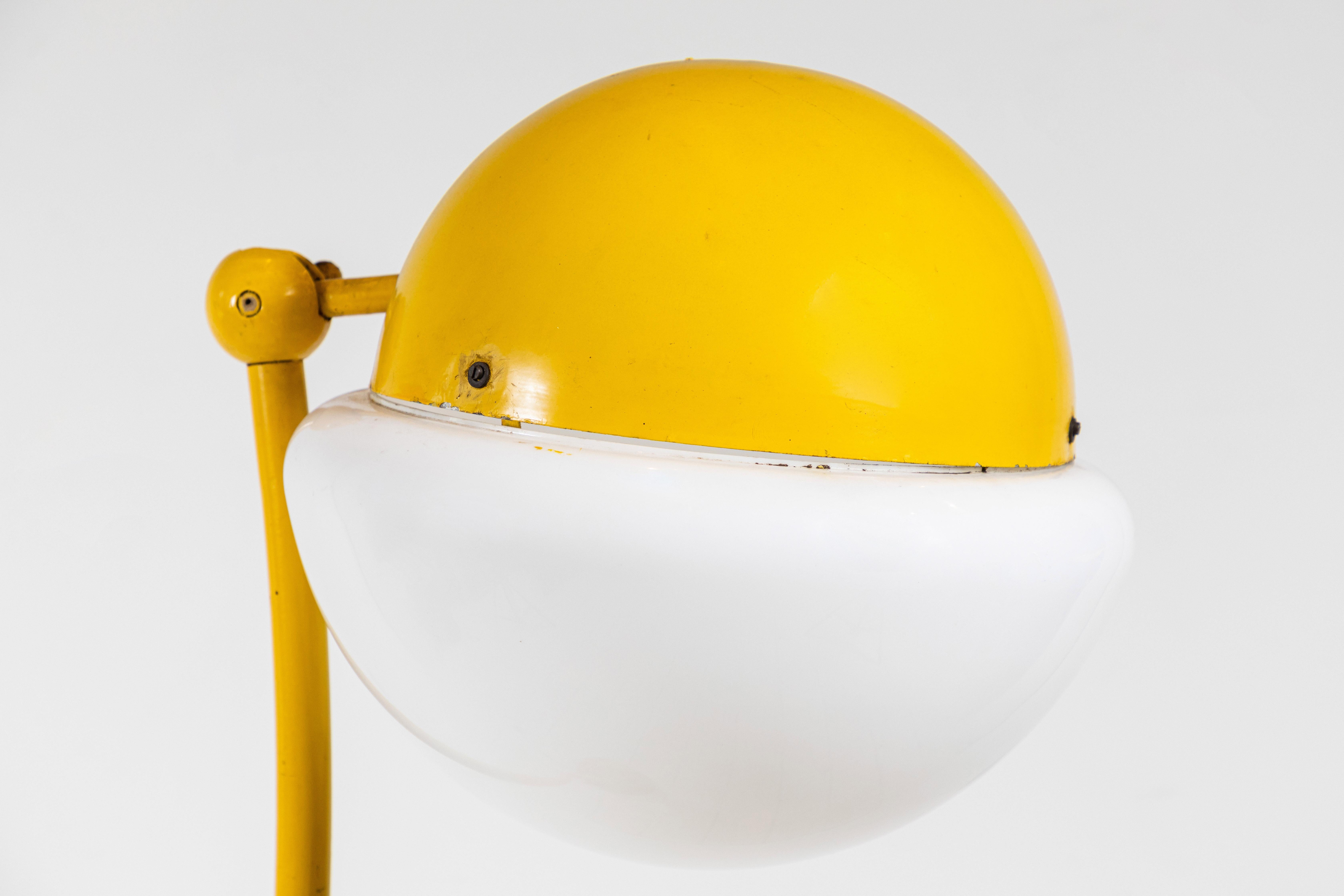 Original yellow paint adds character for the metal Locus Solus floor lamp by Gae Aulenti. The lamp has been newly rewired. The lamp has an adjustable neck and the head pivots up and down.
