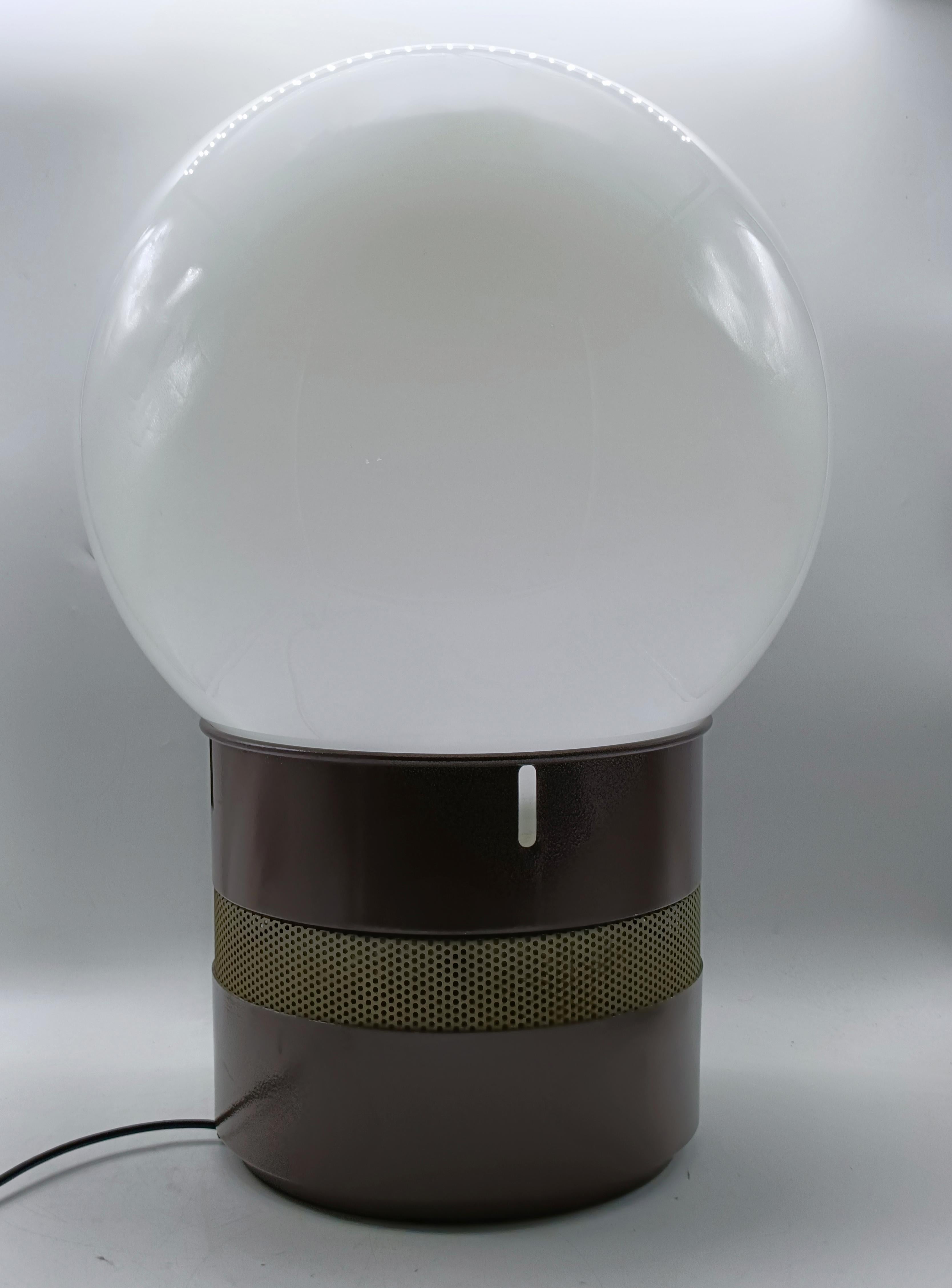 Lámpara de mesa Mezzoracolo, en metal lacado marrón, pie y difusor en metal opalino blanco.
Perfectamente conservada y funcional con luz interna en la base y en el difusor.
Producida por Artemide en 1969.