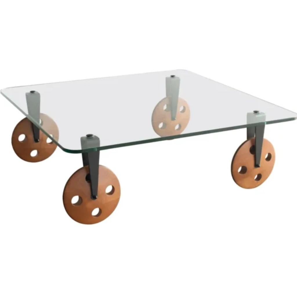 Handsome, Industrial, Tavolo Con Ruote Coffee Table, created by Garn Aulenti for Fontana Arte, Italy, in 1980. 

This table is known for its unique design, featuring a glass top supported by four large, wooden wheels. 

The wheels are not just