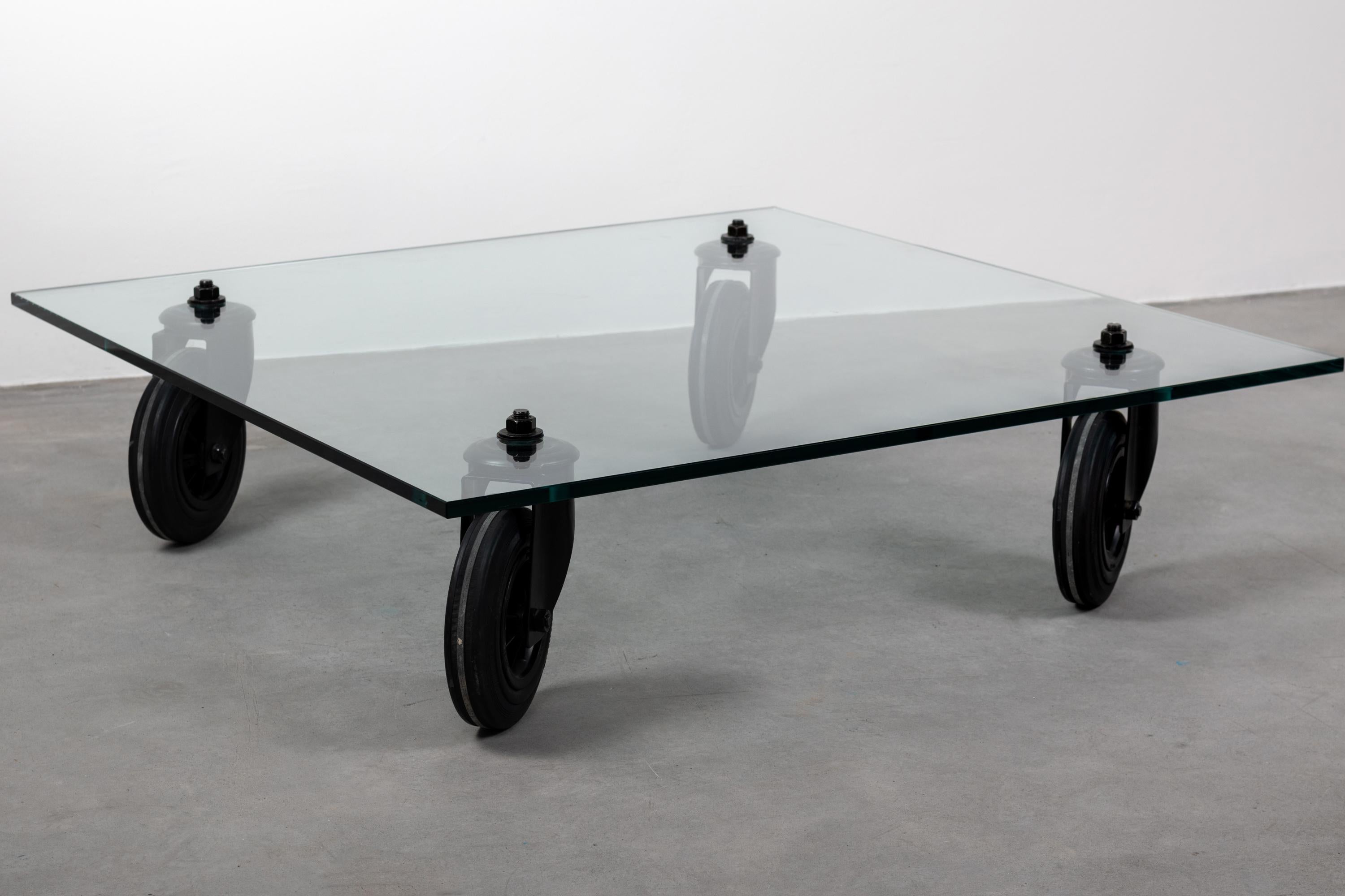 A square coffee table with tempered glass top, supported by four wheels mounted on a painted black metal structure. 
Designed by Gae Aulenti for Fontana Arte, 1980. 



 