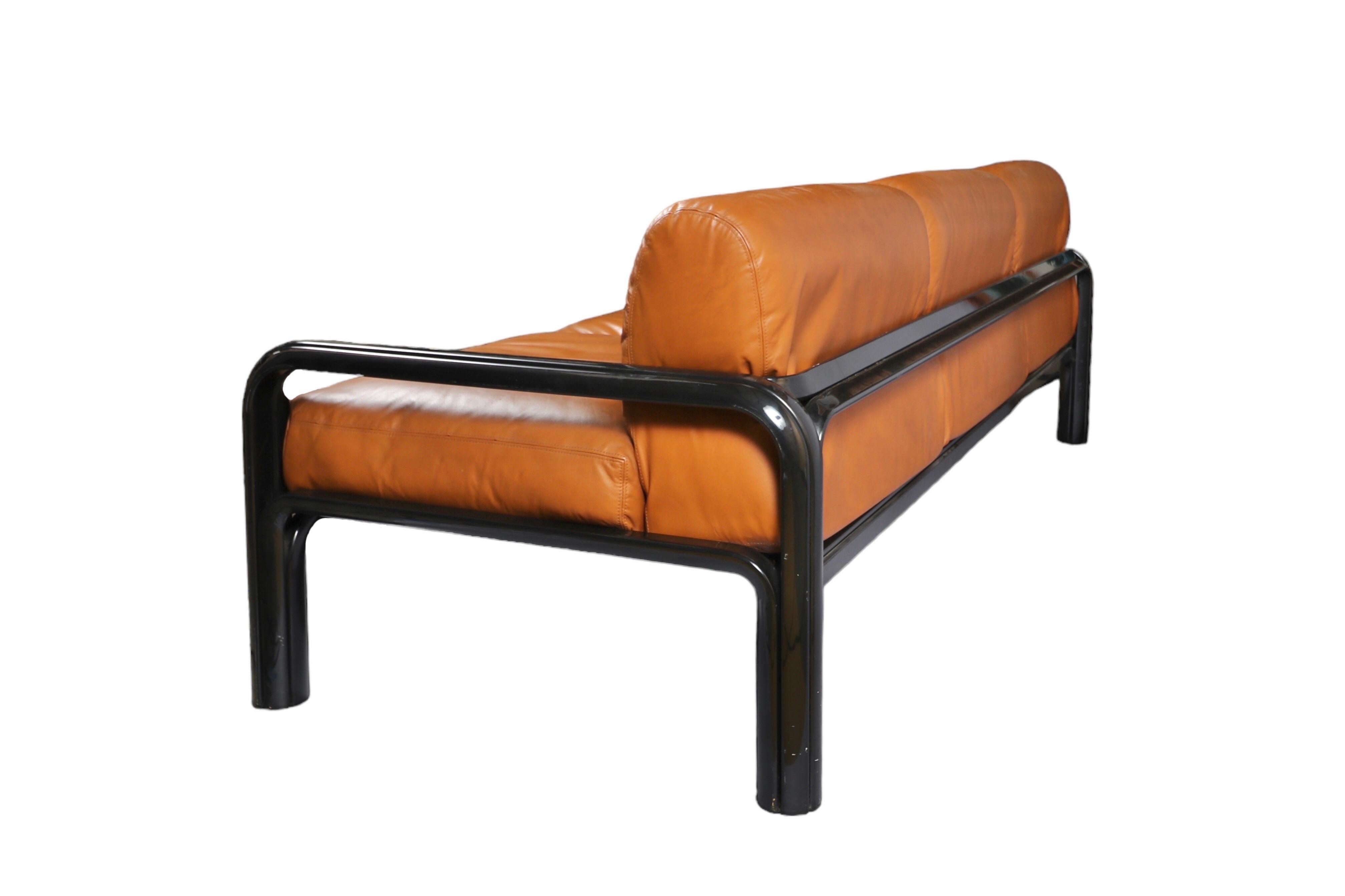 Three seat sofa by Gae Aulenti (b. Palazzolo Dello Stella 1927 - Milano 2012).

Produced by Knoll International, USA, circa 1970.

Features removable Cognac faux leather seat and back cushions, black lacquered metal frame.

Arm height, 21.5” H;