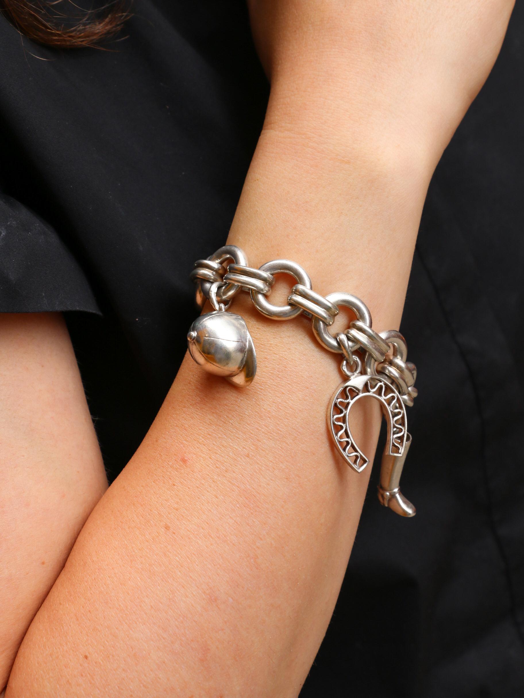 Bracelet en argent avec alternance de maillons ronds et rectangulaires godronnés retenant plusieurs médailles sur le thème équestre : une botte d'équitation, un fer à cheval, une bombe de casque, un étrier et une cravache.
Ouvrage français des
