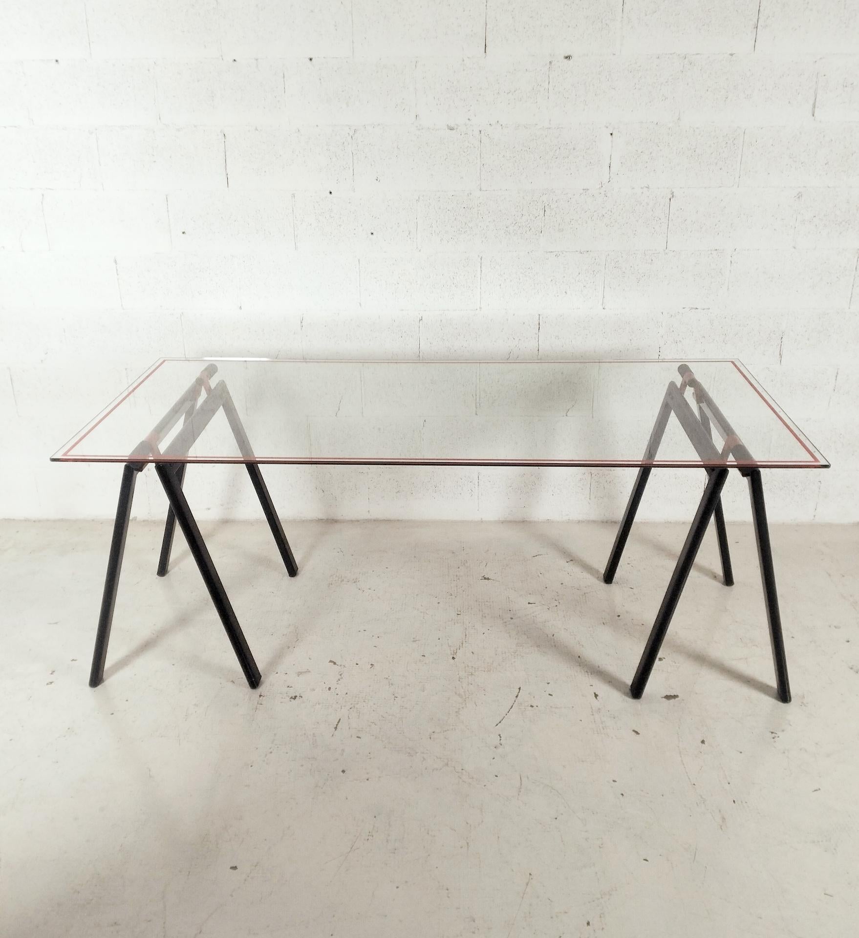 Arbeitstisch Gaetano von Gae Aulenti für Zanotta mit originaler Glasplatte, die von zwei Klappböcken aus schwarz und rot emailliertem Metall getragen wird. Zeitloses Objekt. Mit seinem trockenen und essentiellen Design verbindet er Modernität und