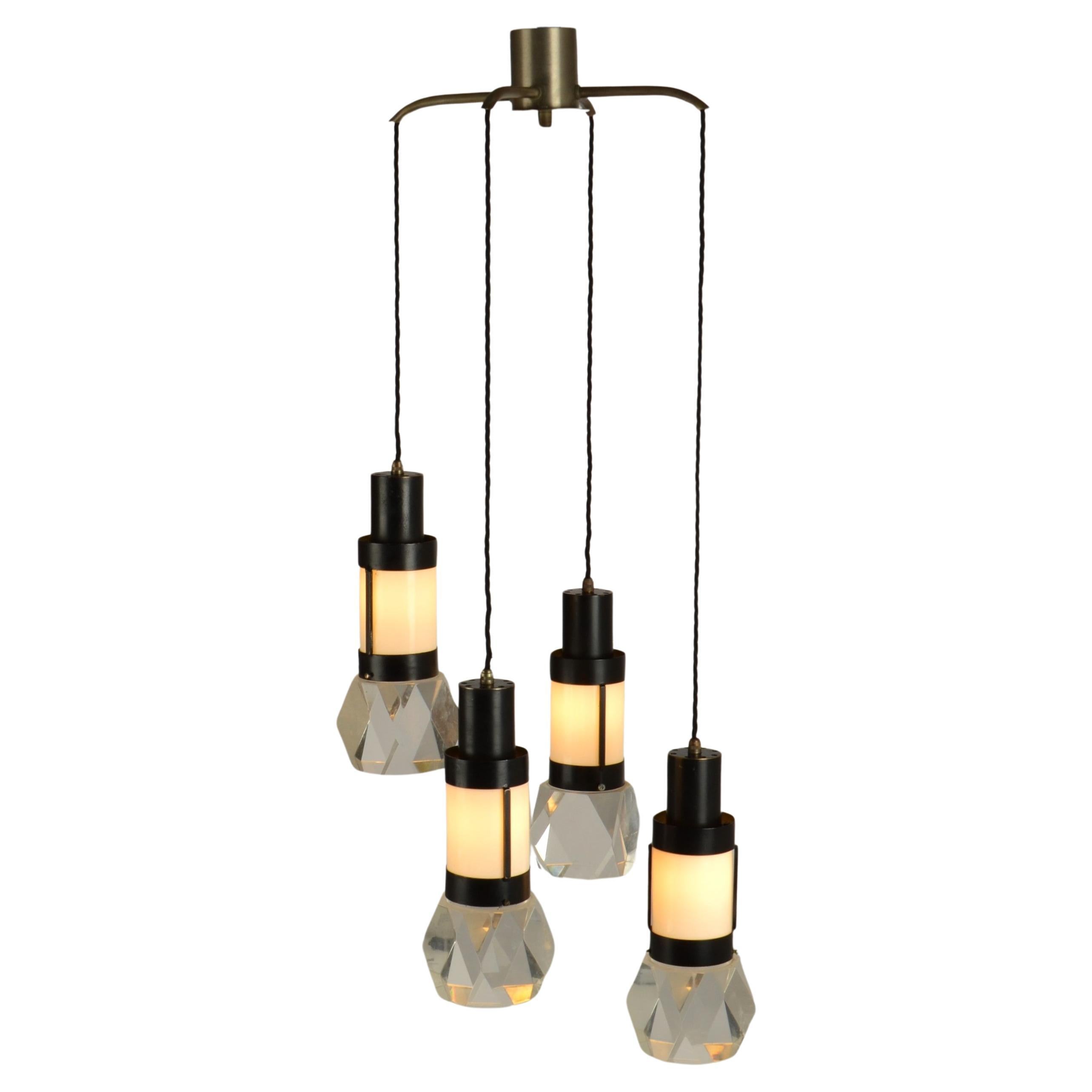 Chandelier with four pendants in nickel plated and black metal  frame with white perspex diffuser and polyhedral shaped lucite / plexiglass shades, designed by Gaetano Missaglia and manufactured in Italy 1960s. The luminous suspensions contain a