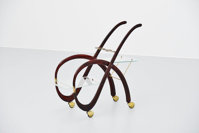 Fantastic organic shaped serving bar cart designed by Gaetano Pizzi, Italy, 1950. This cat has a solid mahogany frame with brass details and glass serving trays. The cart rides perfectly in its brass rubber wheels and is fully original and in