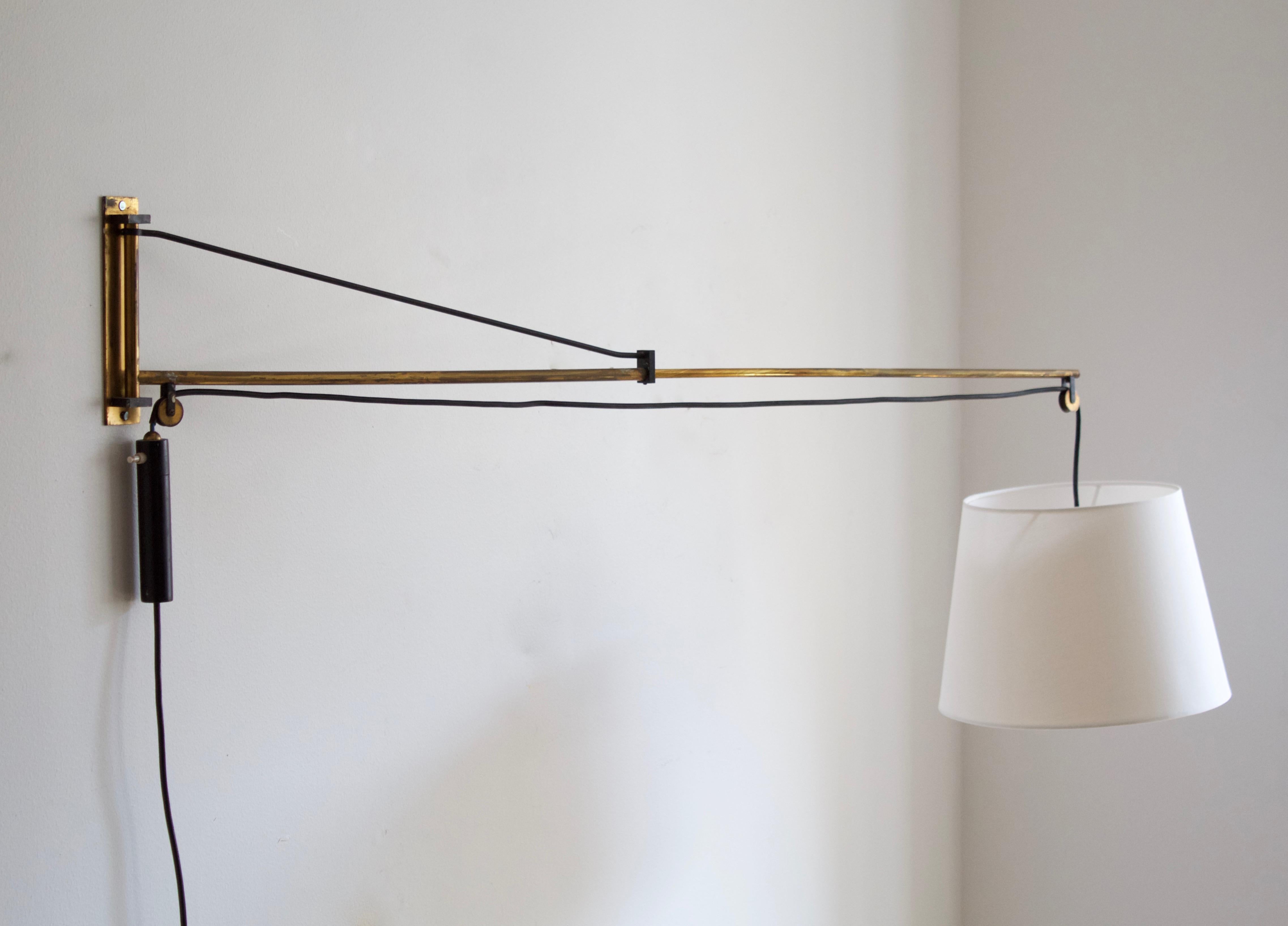 A sizable wall light designed by Gaetano Sciolari, produced by Stilnovo, Italy, in 1954. Features brass and black lacquered metal. Originally with a metal lampshade, this example with a brand new fabric lampshade. Stated dimensions include