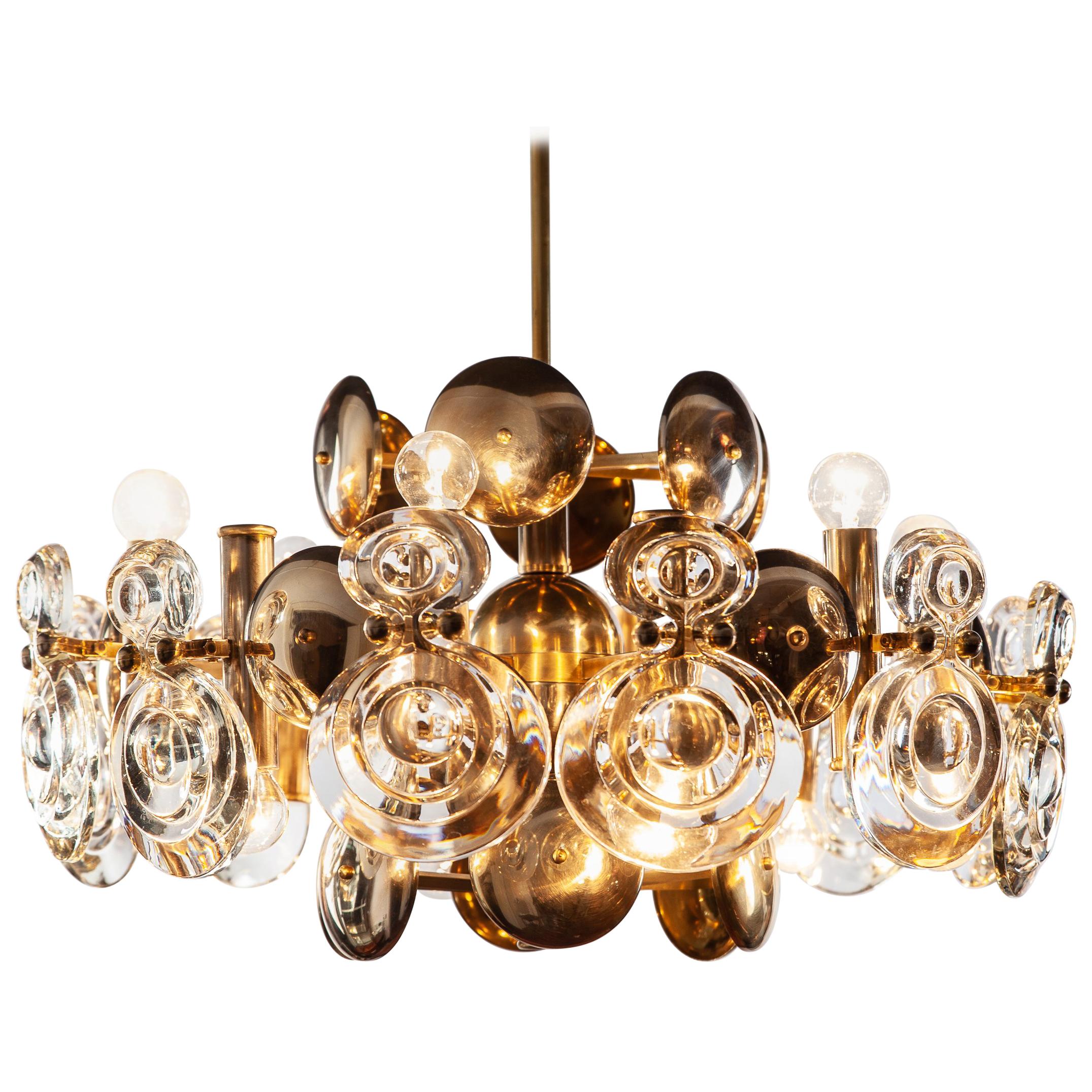 Italian, large midcentury Gaetano Sciolari two-tier chandelier featuring in the original brass finish. Fine optic glass lenses are decoratively and functionally mounted on unusually shaped concave metal shields to serve as reflectors. Top tier holds