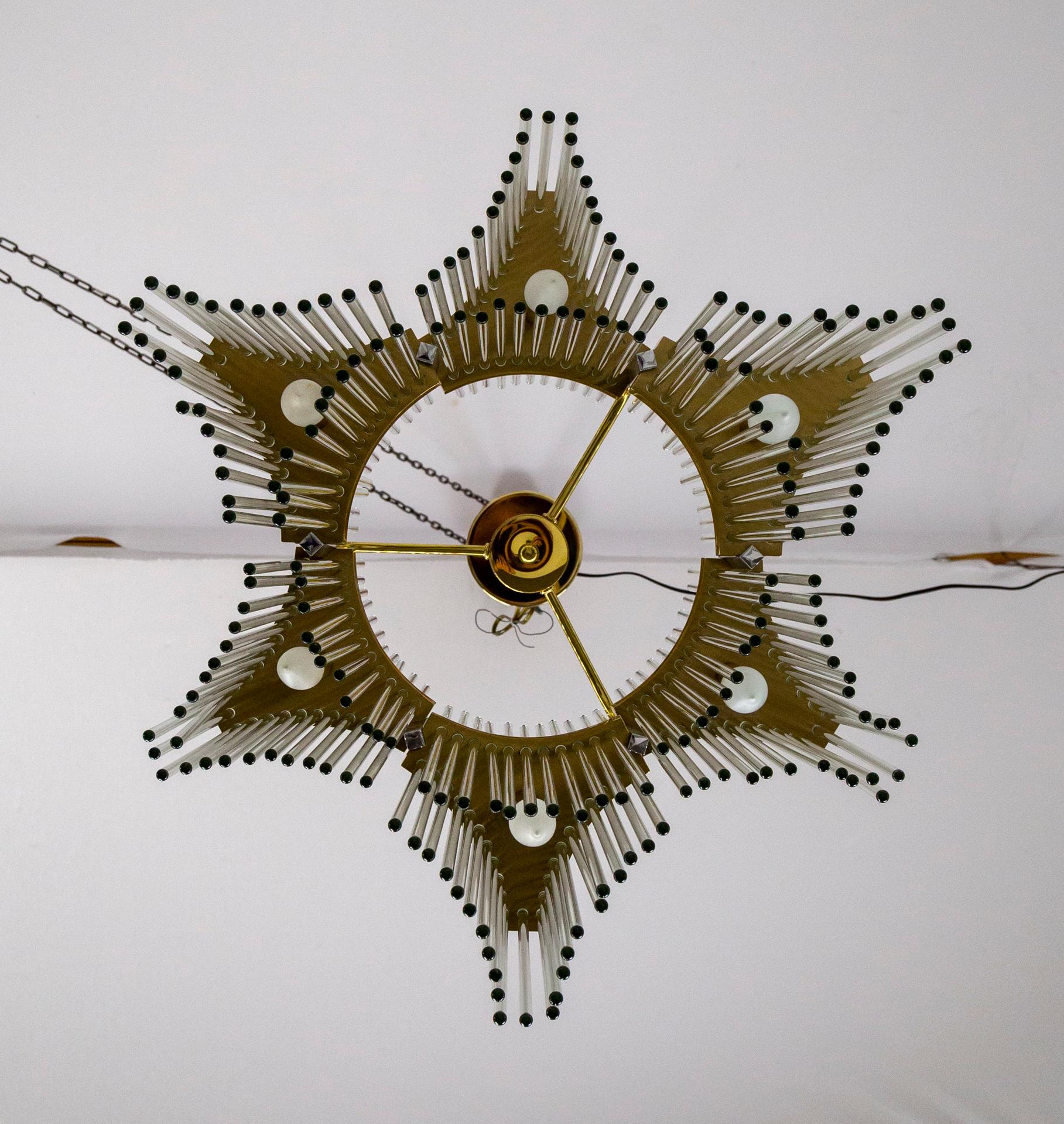 An iconic, Gaetano Sciolari, glass rod chandelier from the 1970s. Six groups of hanging rods in alternating heights, with 2 sockets each (one bulb pointing up, the other down), banded with brass. It forms a star shape when seen from below based on