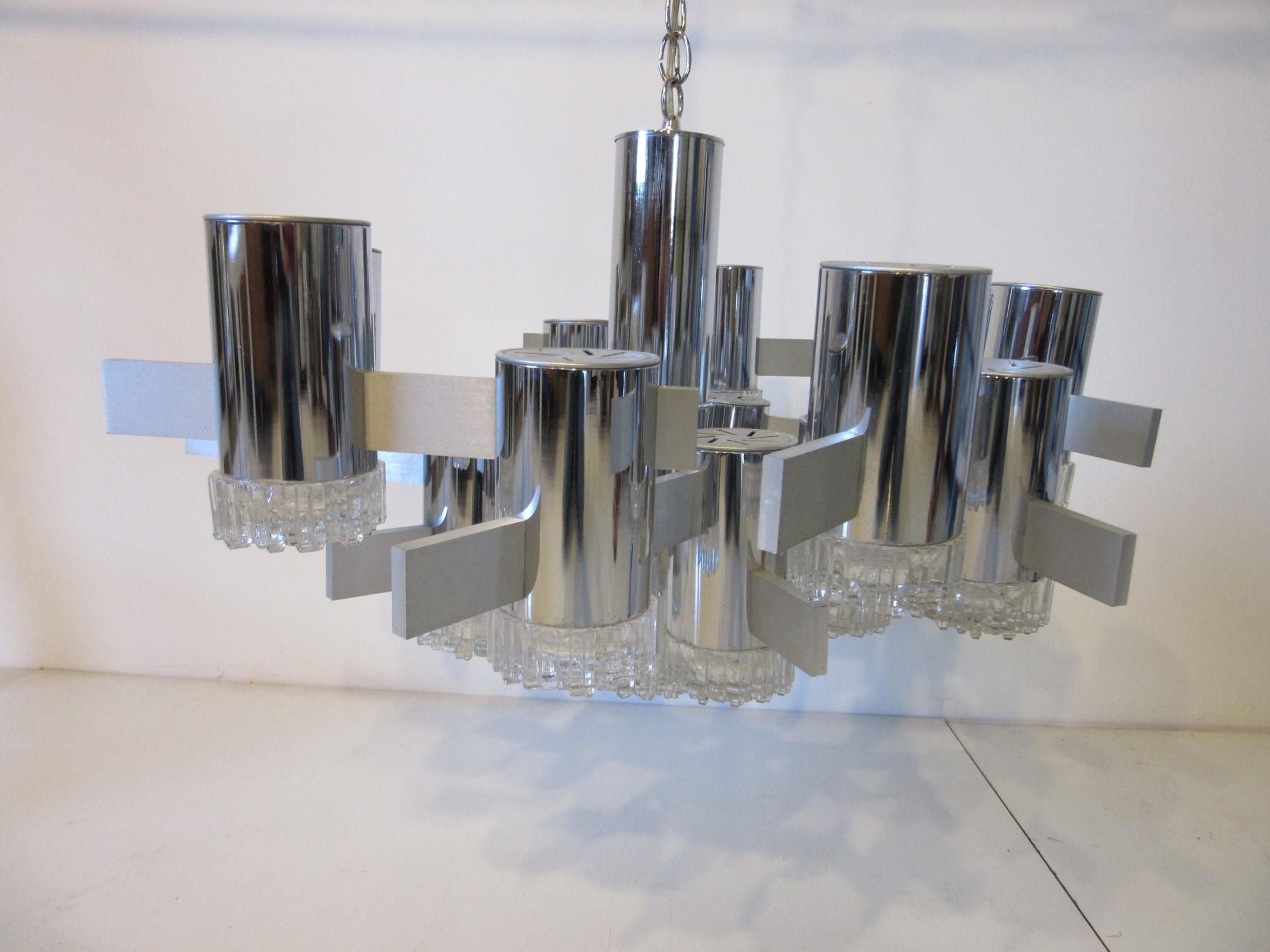 A chrome tubed hanging light fixture with 16 molded glass patterned lamp ends tied together by brushed aluminum bars . This impressive piece of sculptural lighting would enhance any entrance way, dining room or large area , can be hung at any height