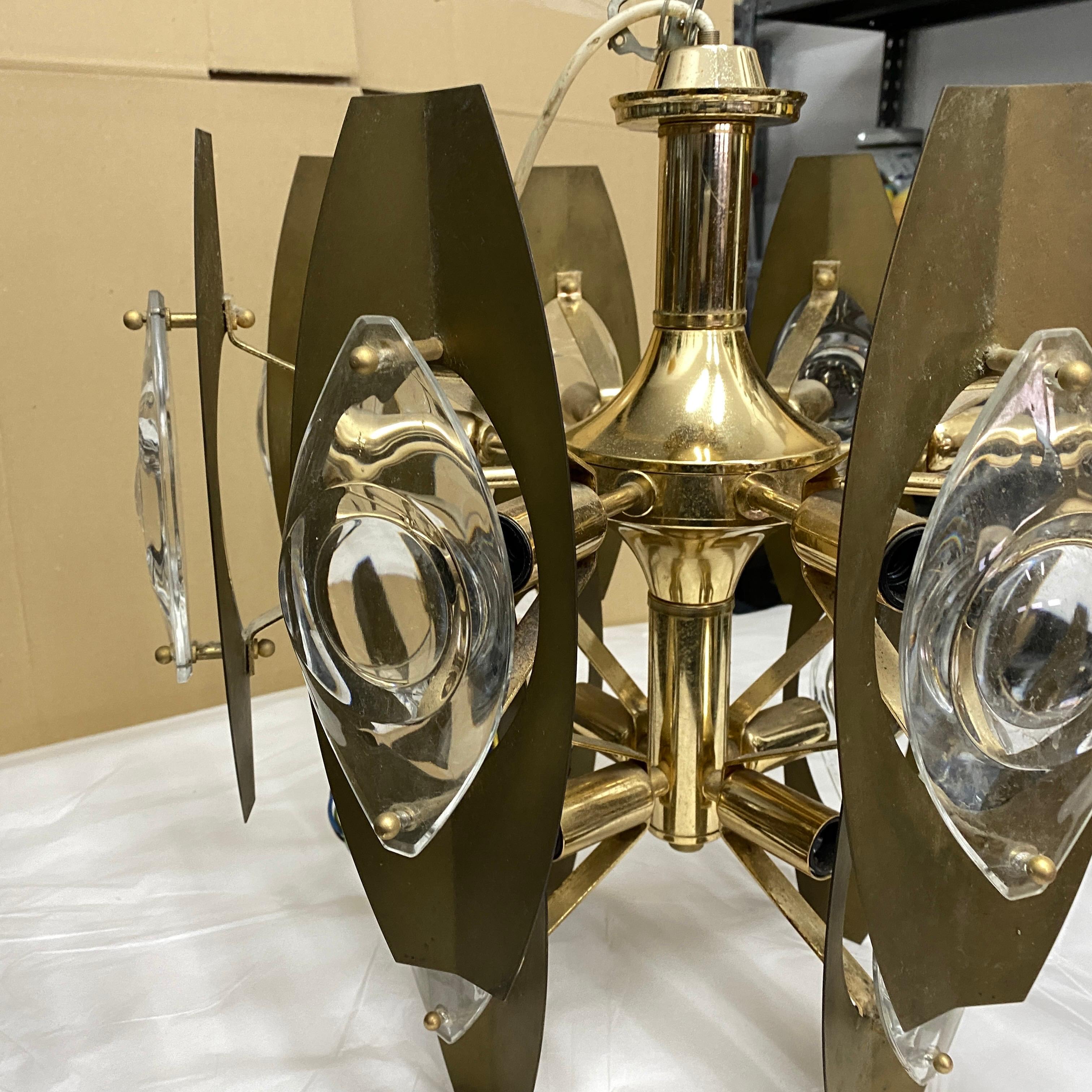 An amazing 8 lights chandelier by Gaetano Sciolari. It's made in brass and optical glasses, brass it's in original patina and glasses are in perfect conditions. It works 110-240 volts and needs regular e27 bulbs.