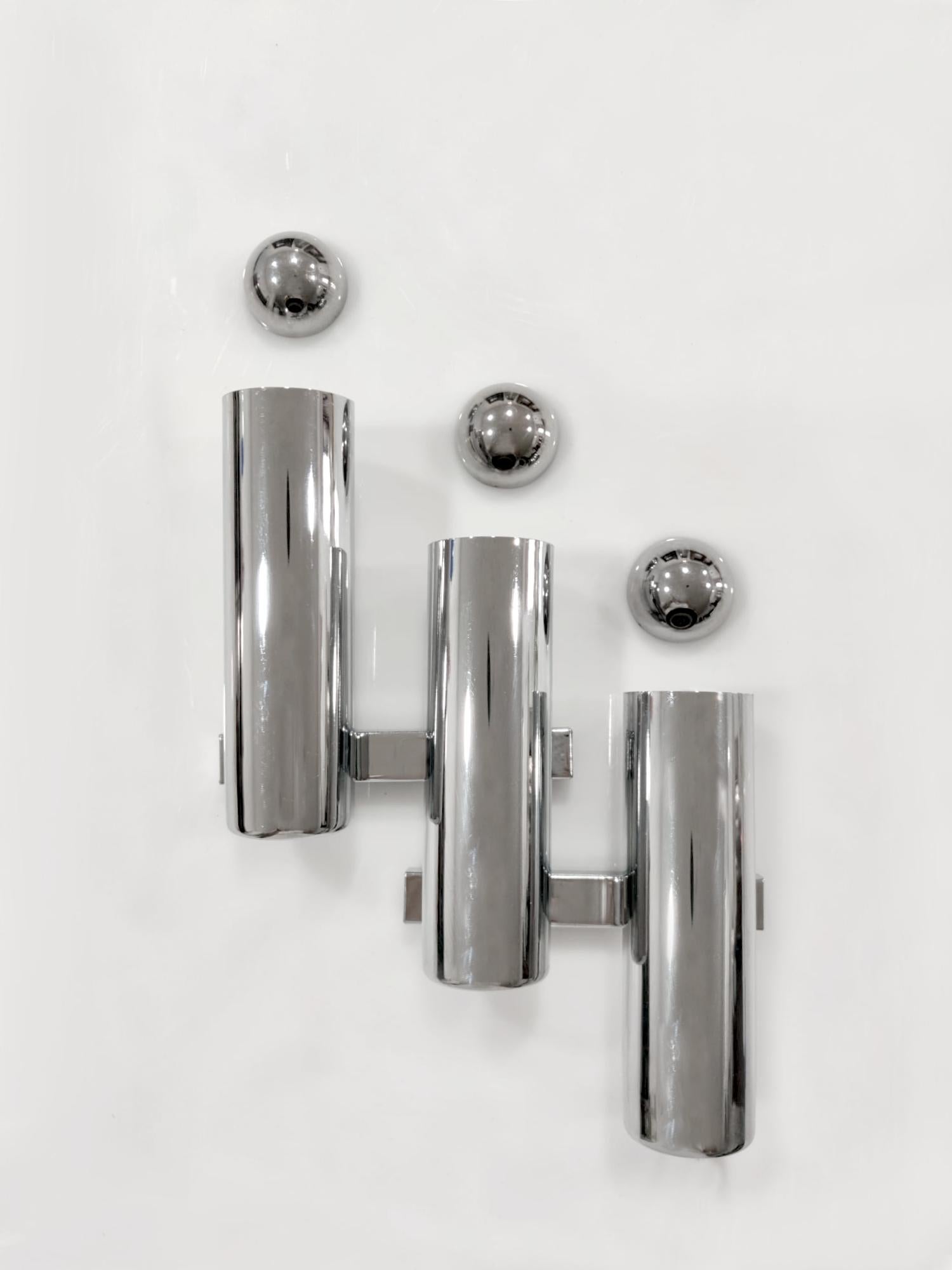 Aplique de pared diseñado por Gaetano Sciolari en Italia durante la década de 1960. Su estructura geométrica es de metal cromado, con tres cilindros verticales escalonados que proyectan la luz hacia arriba y hacia abajo. El rasgo definitorio, que le