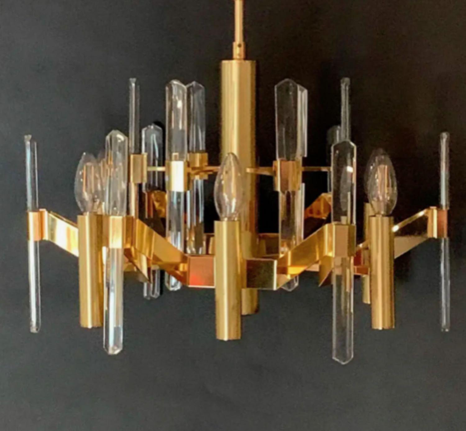 Six-light chandelier by Gaetano Sciolari. Gold-plated brass and vertical faceted crystals. The sculptural forms and striking geometric details of his chandeliers and other fixtures fit seamlessly into the Mid-Century Modern interiors of the day.