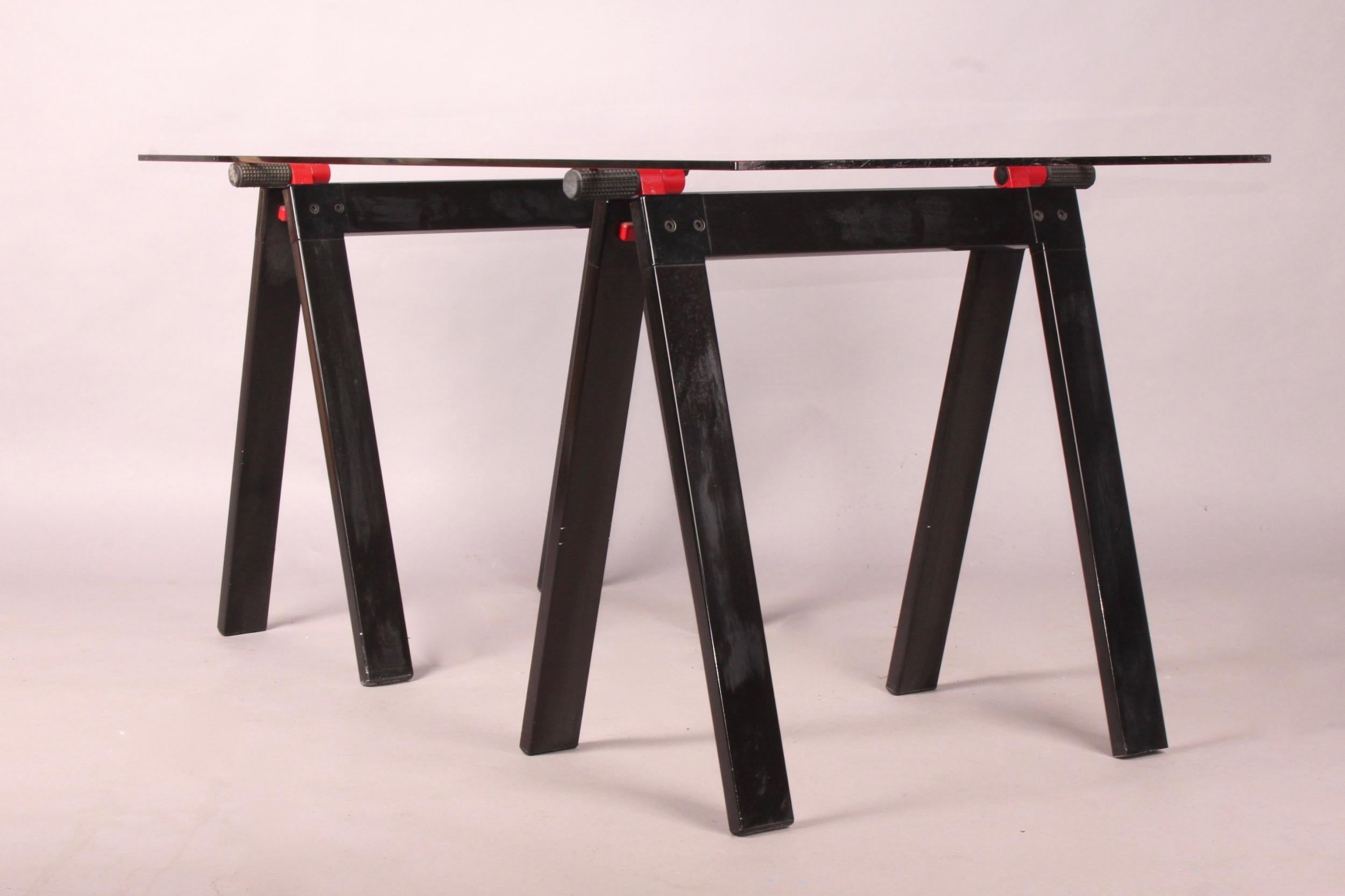 Gaetano working table by Gae Aulenti for Zanotta with original glass top, supported by two black and red enameled metal folding working horses alike base, one plastic base is missing.
