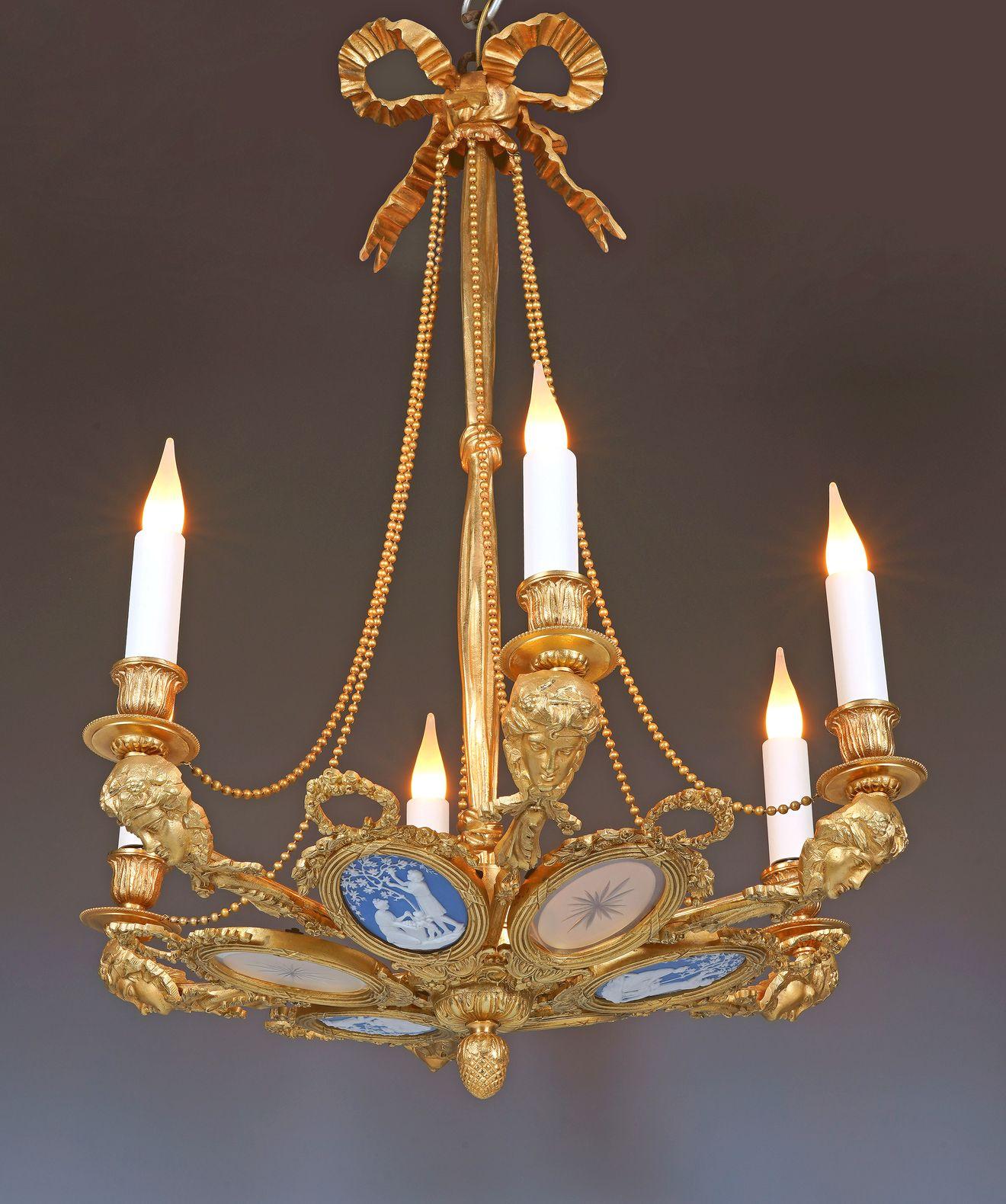 Encantadora araña de bronce dorado de inspiración Luis XVI con seis luces atribuida a Gagneau. Está formado por seis medallones ovalados rodeados por un toroide acanalado y rematados con guirnaldas de flores, alternando entre una placa de vidrio