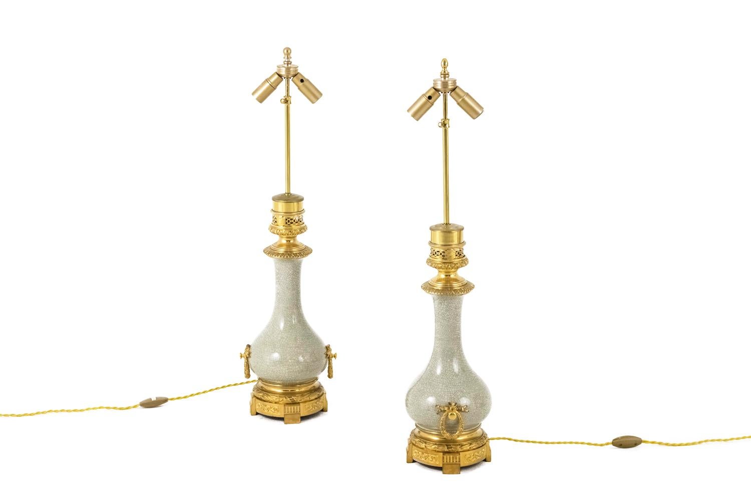 Pair of bottle shape Louis XVI style lamps in cracked beige celadon porcelain.
Chiselled and gilt bronze mount. High part with a decor of leaves friezes, twisted ring and geometrical openwork motifs. Decor of laurel wreath fixed by a ribbon forming
