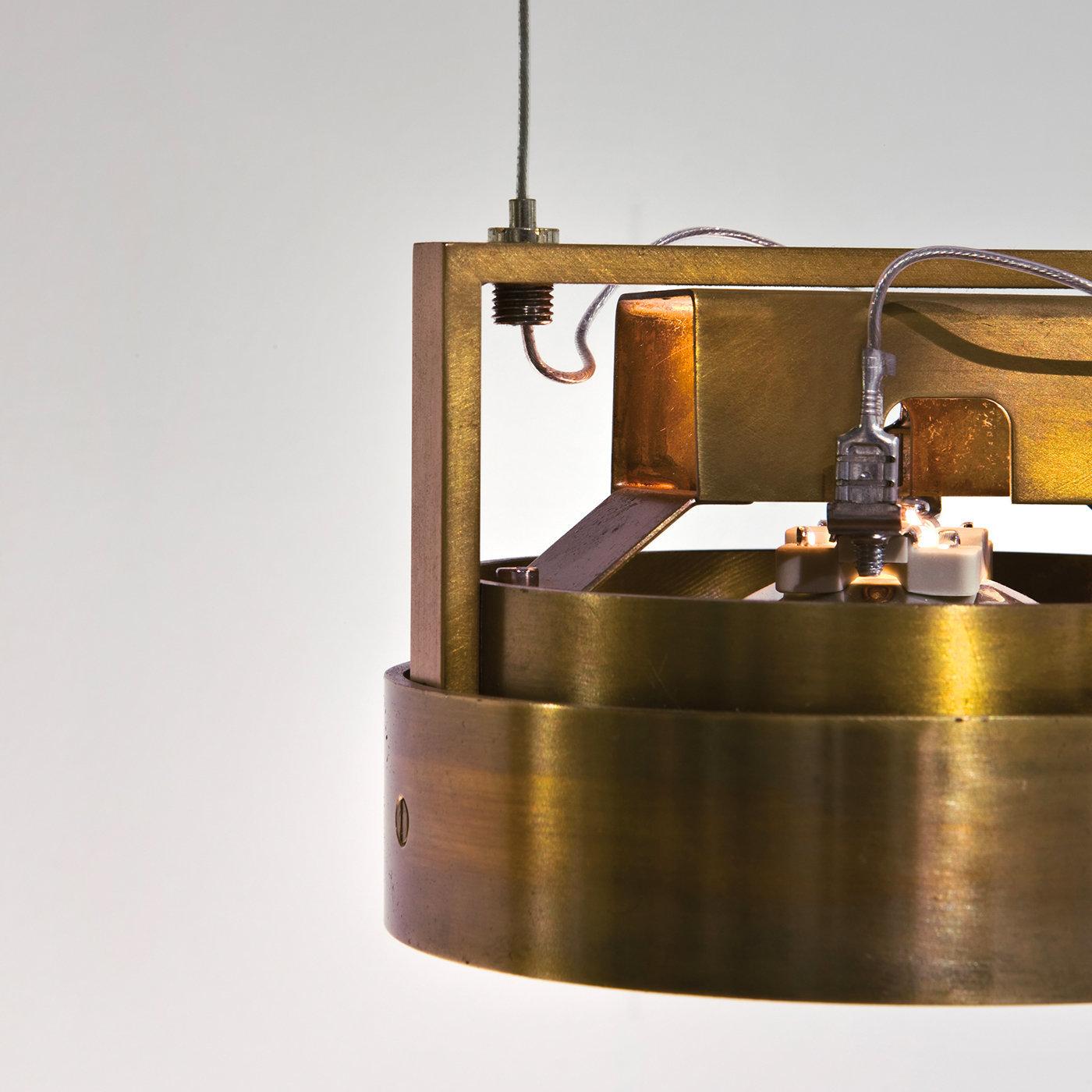 This elegant spotlight is in burnished brass and is perfect to hang from any type of ceiling to illuminate a variety of interiors, thanks to its adjustable height. The linear design and use of precious materials are staples of Laura Meroni and this
