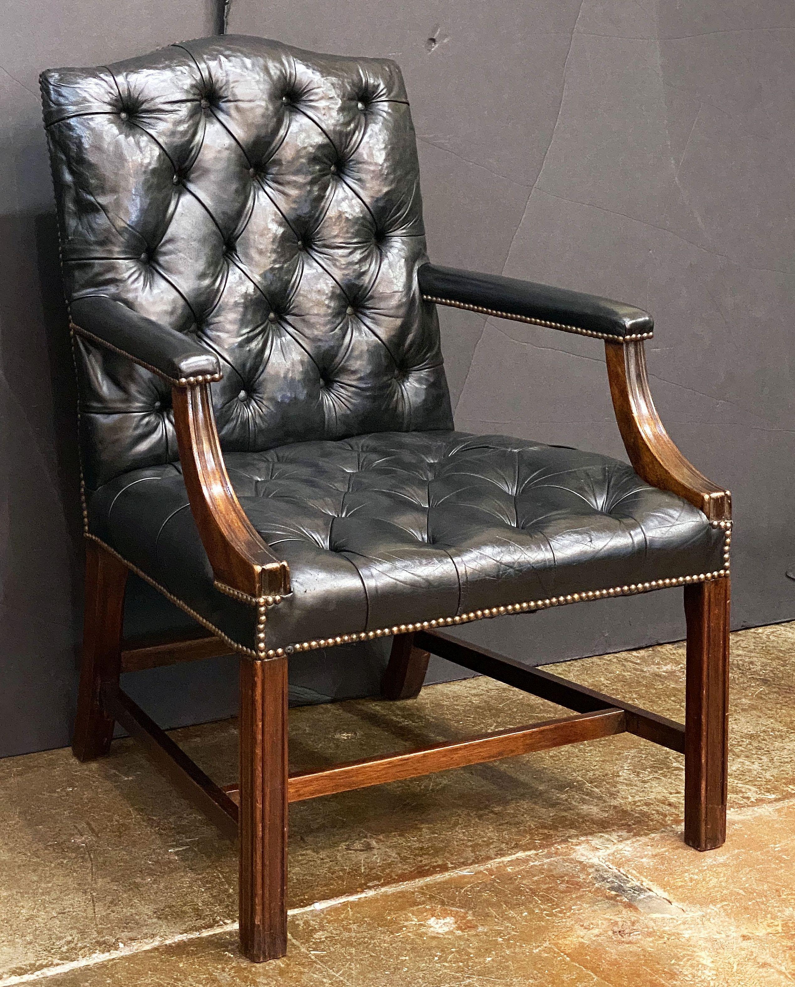 A fine Gainsborough armchair or lounge chair upholstered in black leather and patinated mahogany from England  - featuring a high back, open sides and shaped arms, with wide comfortable seat, on a mahogany stretcher.

The leather upholstery with