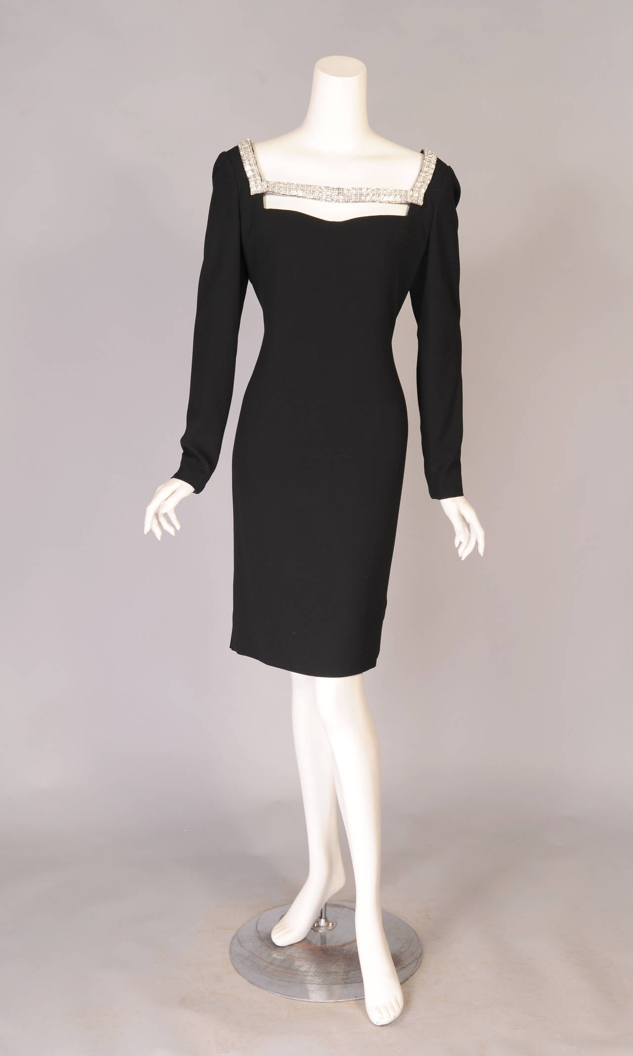 Black silk crepe is used for this classically elegant long sleeved dress with a square neckline. The neckline is enhanced with a double row of sparkling faceted 