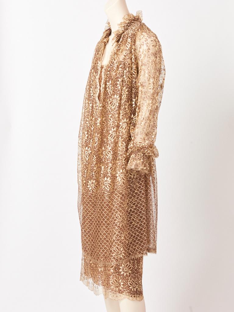 James Galanos, 2 piece bronze tone, diaphanous, floral pattern lace ensemble. The ensemble consists of long sleeve tunic having a  deep V neck and a ruffle collar, which sits over a slip dress in the same lace pattern, having a mocha tone chiffon