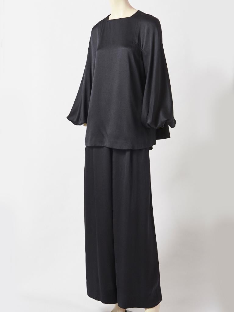 Galanos, black, satin back crepe, pyjama top and pant ensemble. Top is smock like, with a high, square neck line and ends below the hip, having full sleeves that gather above the wrist and hidden pockets at the side. The back of the top is fuller