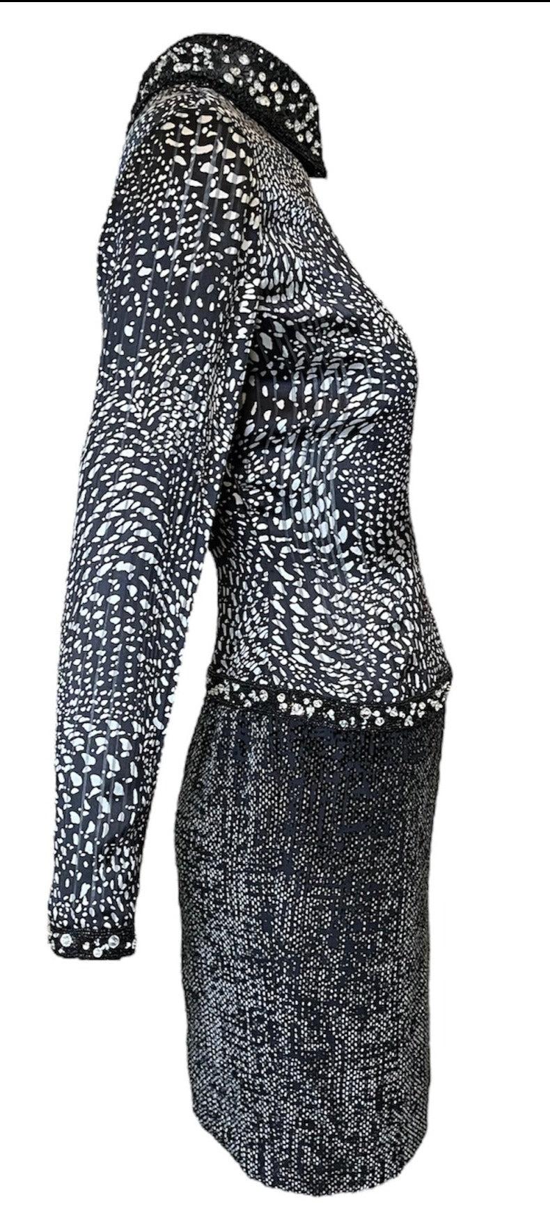 From James Galanos, circa the 1980s, this black and white cocktail dress features a luxurious silk jacquard top with a bold abstract pint and a textured  black and  white velvet skirt. Dazzling sequins, beads, and faceted diamanté adorn the peter