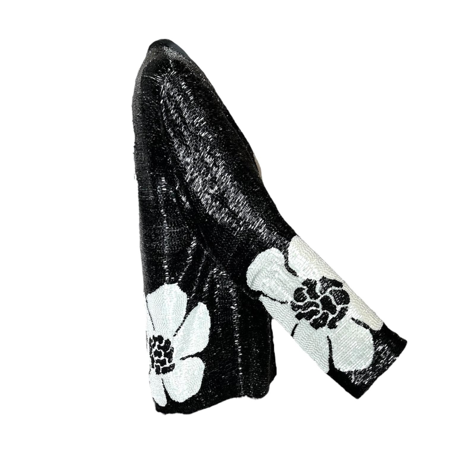 This 1970's Galanos jacket is truly an exquisite display of craftsmanship. Dense beading of black and white bugle beads make up a jumbo floral motif. Fully lined in luxurious silk chiffon. Excellent condition, some yellowing on the very delicate