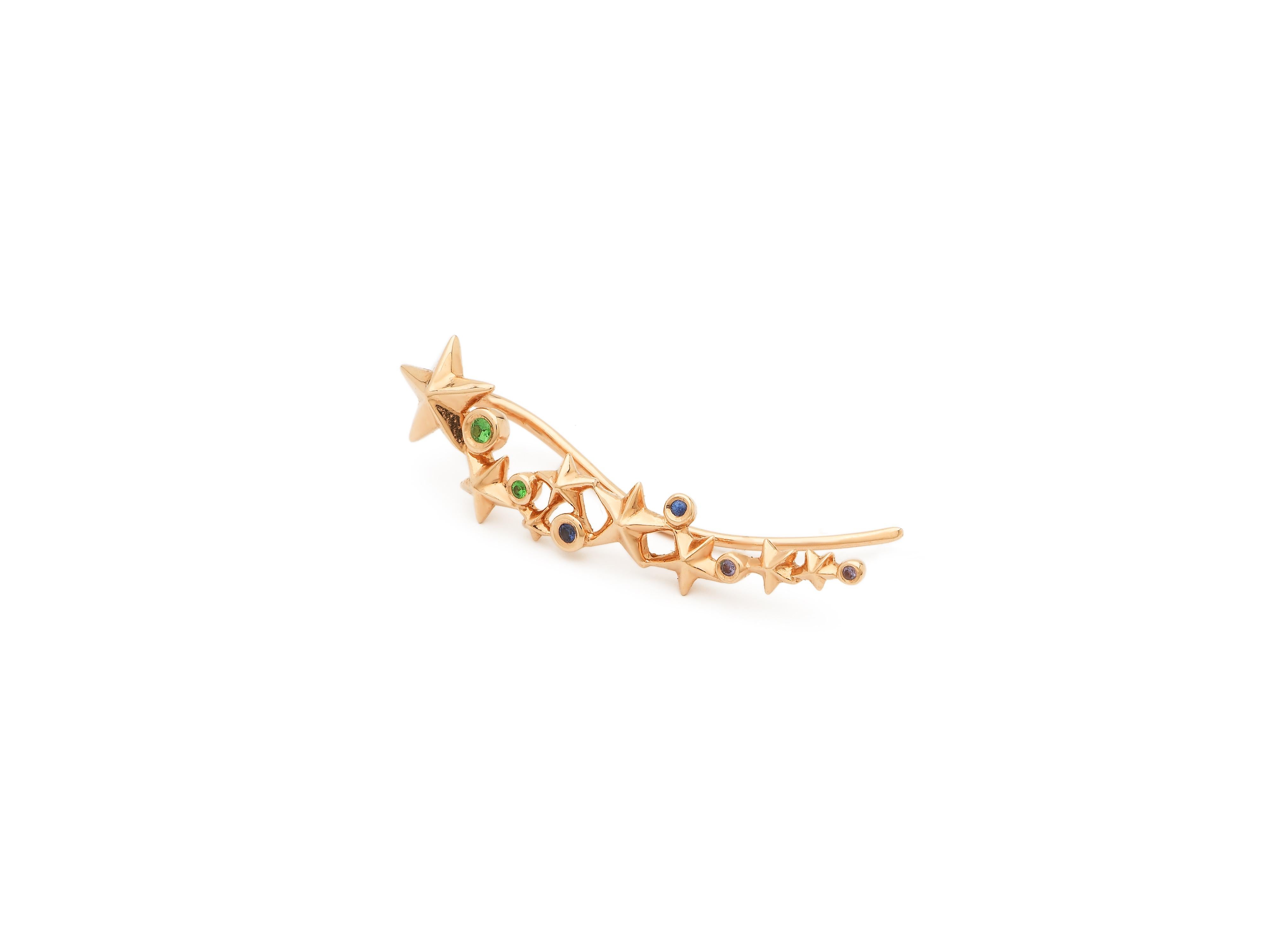 Designed in 18k rose gold, this ear climber pierces the ear once but creates the illusion of multiple piercings on the lobe. Fashioned as a series of stars that climb up the ear, the ear climber is set with blue sapphires, tsavorites, and amethysts,