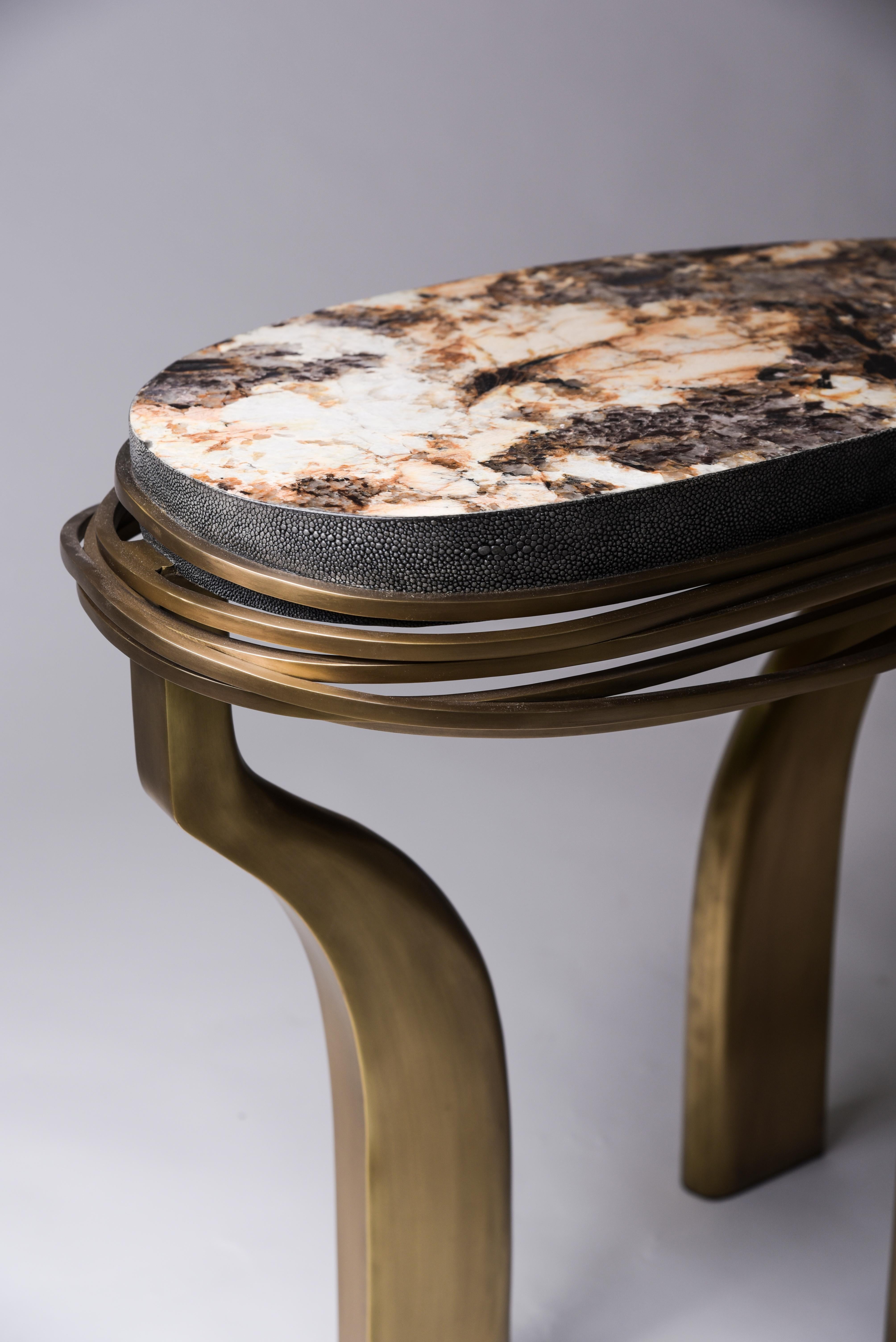 The galaxy side table in large is an iconic Kifu Paris piece. Whimsical, sculptural and bold this piece makes the ultimate accent piece in any space. The intricate bronze-patina brass rings encircle the semi-precious stone (Hwana) inlaid top. The