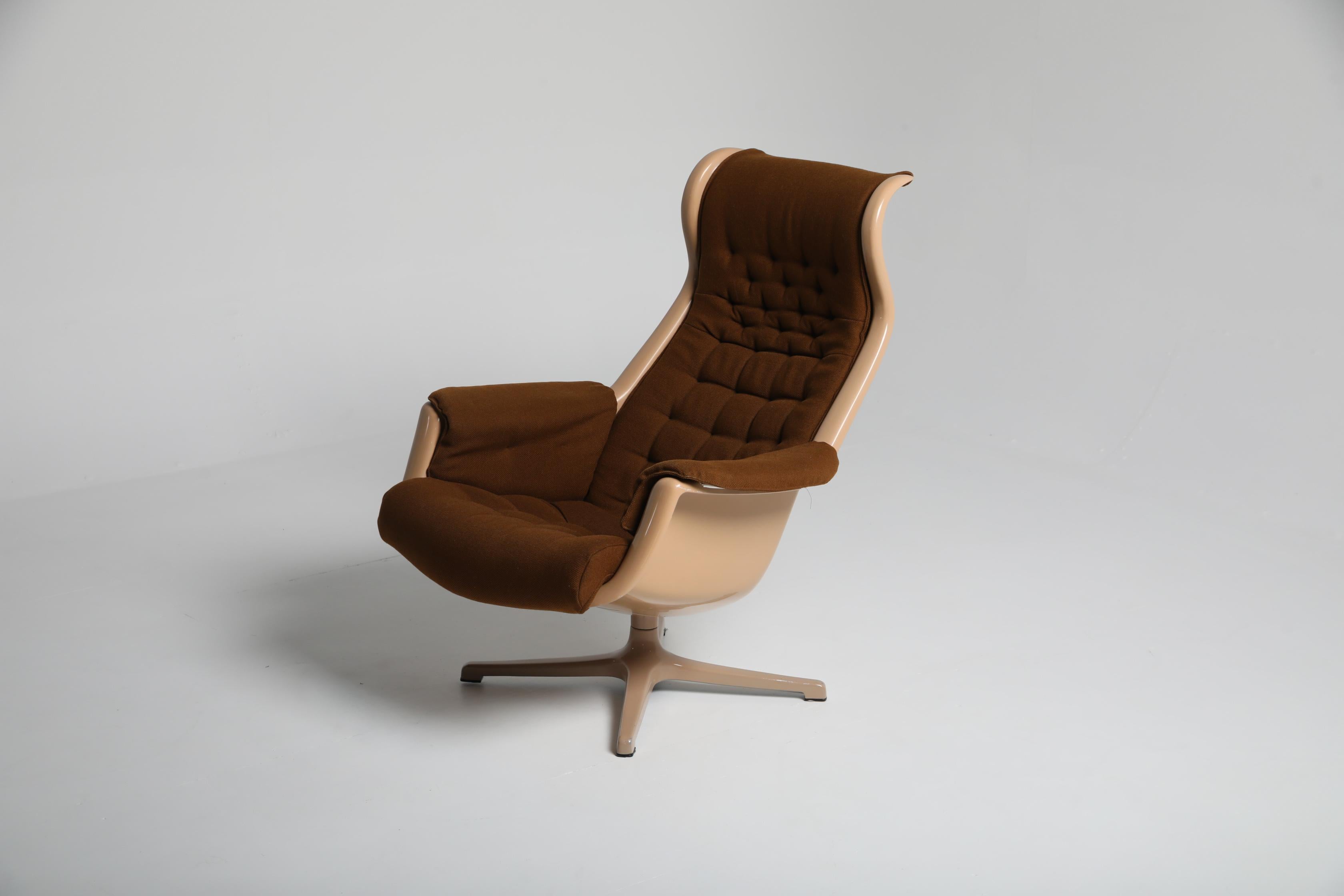 Conçue par Alf Svensson et Yngvar Sandström pour DUX dans les années 1970, la chaise longue Galaxy se compose d'une coque en plastique moulé, d'une assise et d'un dossier séparés et rembourrés en textile brun amovible. La chaise repose sur sa base