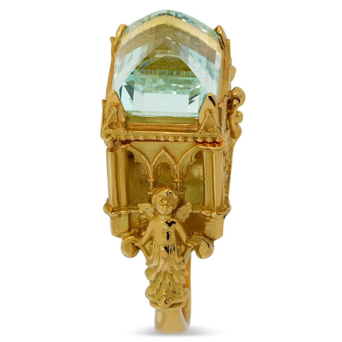 Flanked by two guardian angels and sitting aloft a gorgeous soft rounded split shank, this stunning gothic cathedral ring exquisitely handcrafted in 18kt yellow gold features a latched chamber topped with a divine 8.66 carat powder blue 12.45mm (L)