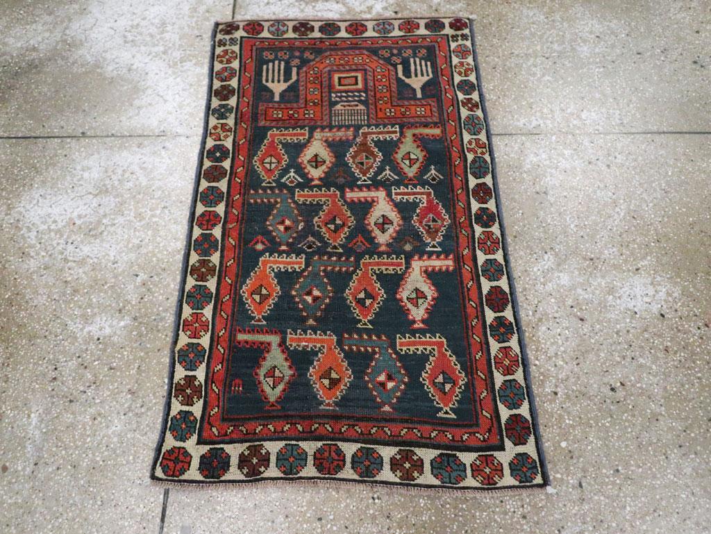 A wool pile of symmetric knots on a wool foundation. The dark blue field hosts four reversing rows of colorful barbed botehs, under a faceted floating red niche arch decorated with rosettes, with ecru open hands in the spandrels. Cream border of