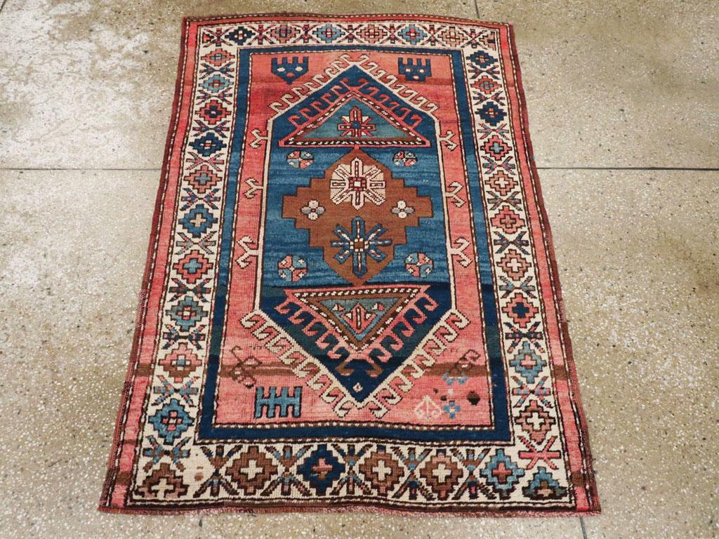 Esta alfombra turca de Anatolia de principios del siglo XX, que mide 1,8 m x 1,8 m, presenta un atrevido diseño geométrico de medallones en una llamativa paleta de añil, rojo ladrillo, marfil y marrón chocolate. El campo central presenta una