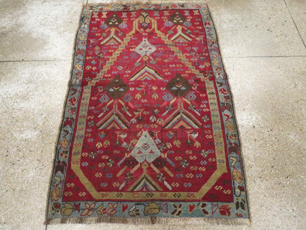 Esta alfombra turca Ghourdes de principios del siglo XX, que mide 1,80 x 1,80 m, presenta un atrevido diseño de oración direccional centrado en un llamativo campo rojo magenta. El nicho escalonado del mihrab está enmarcado por vibrantes motivos