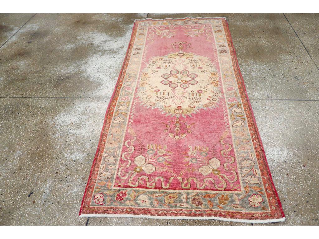 Esta alfombra turca Oushak de principios del siglo XX, que mide 1,80 m x 1,80 m, muestra el renombrado arte de la región y su característico uso del color. El campo presenta un suave fondo rosa que enmarca un medallón central alargado en marfil,