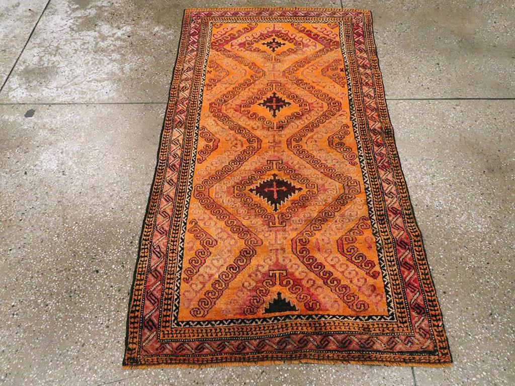 Esta alfombra persa baluch de mediados del siglo XX, que mide 1,80 m x 1,80 m, presenta un vibrante y dinámico diseño tribal que capta el audaz espíritu de las tradiciones de tejido baluch. El rico campo naranja está estructurado en torno a una