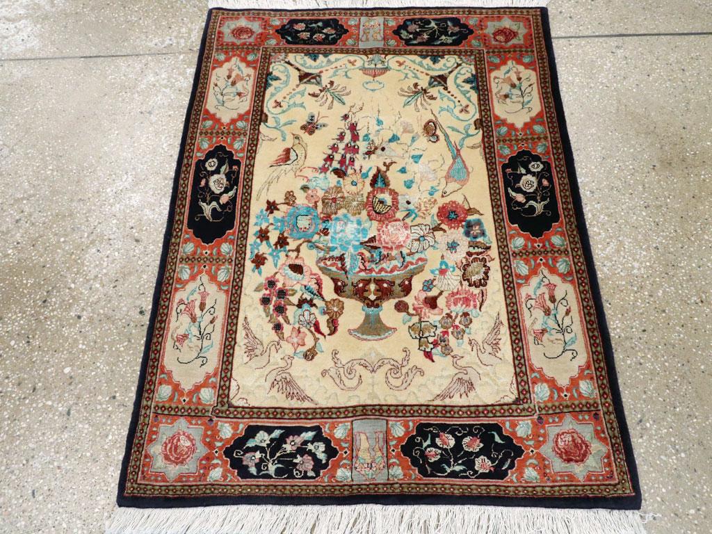 Esta alfombra persa Qom de mediados del siglo XX, que mide 1,8 m x 1,8 m, es una pieza pictórica finamente tejida que muestra la tradición de la región de intrincado arte y lujosos detalles. El campo marfil se centra alrededor de un opulento arreglo