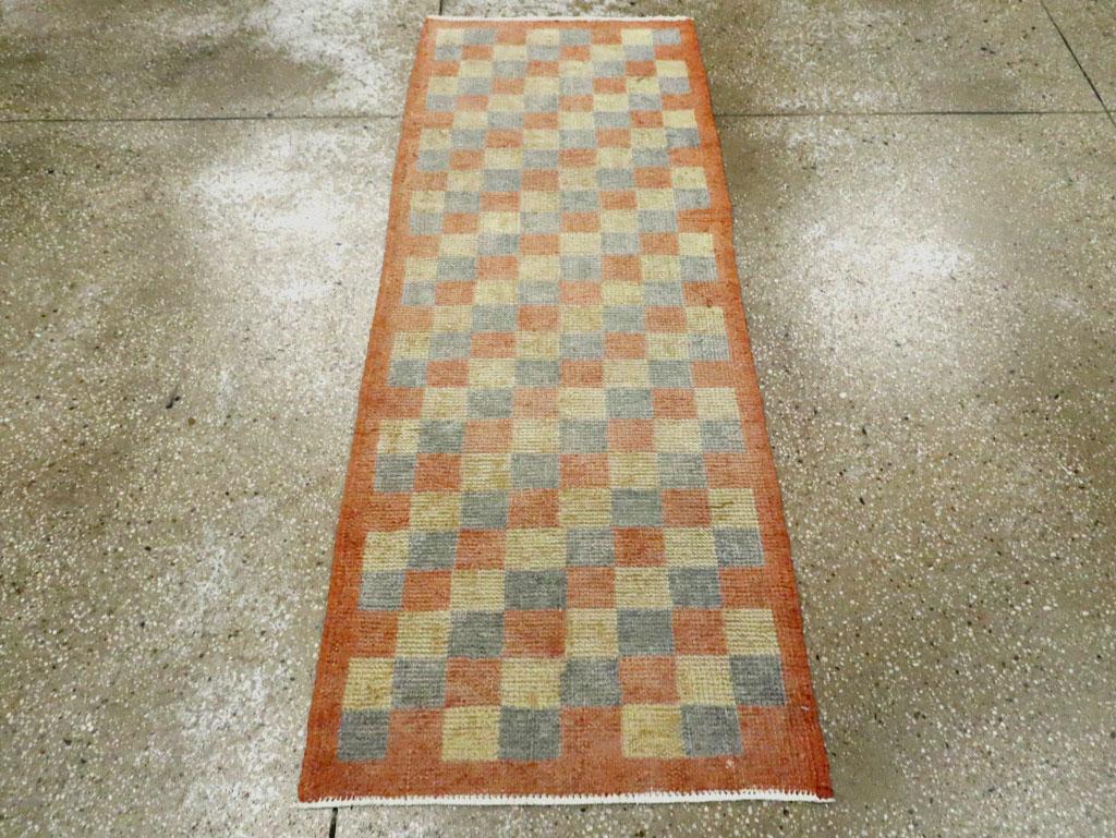 A vintage Turkish Anatolian rug. This can be used as a tiny runner. The allover, squares pattern has a diagonal orientation with three alternating tones of sky blue, straw, and rust, all within a plain rust border. Nothing figurative or