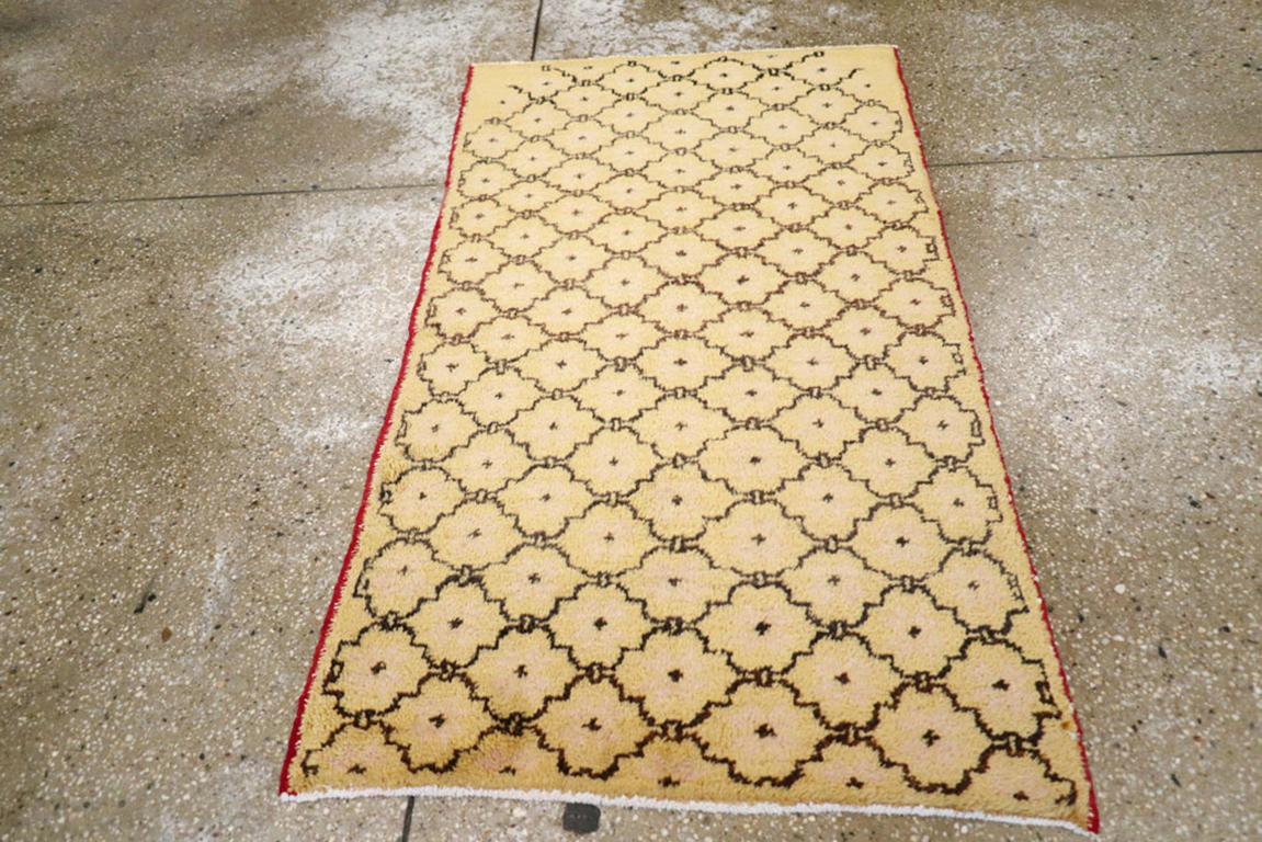 Ein türkisch-anatolischer Teppich im Vintage-Stil. Das elfenbeinfarbene Feld zeigt ein braunes Kartuschengitter, das in den unteren Ecken etwas unsicher beginnt, aber schnell an grafischer Sicherheit gewinnt. Das Gitter ist nur an den Seiten ein