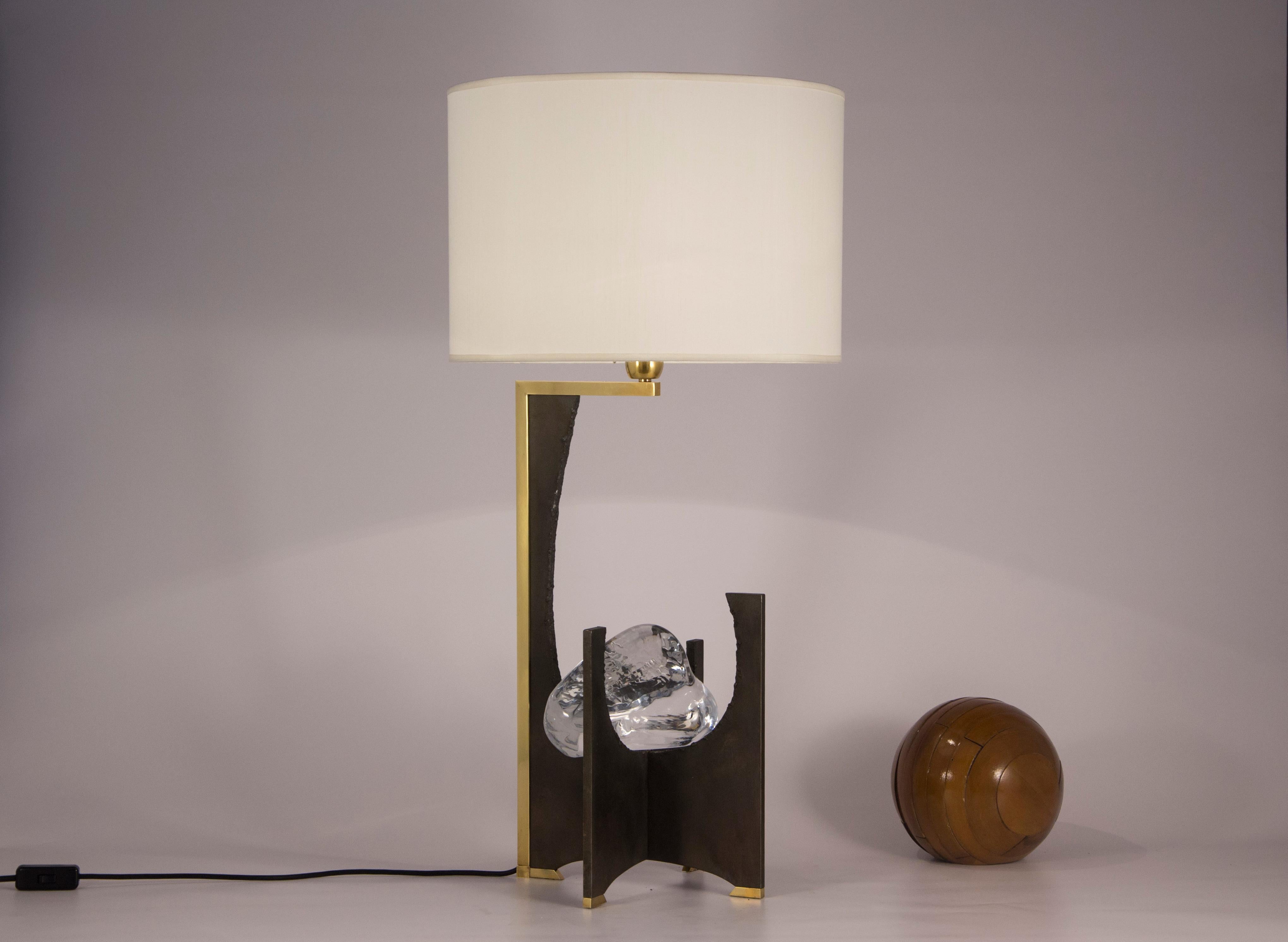 Table lamp with iron structure with natural waxed iron finish. The details of the base and the central body are in slightly burnished brass. In the center there is an artistic crystal made by hand; circular lampshade in ivory colored shantung.