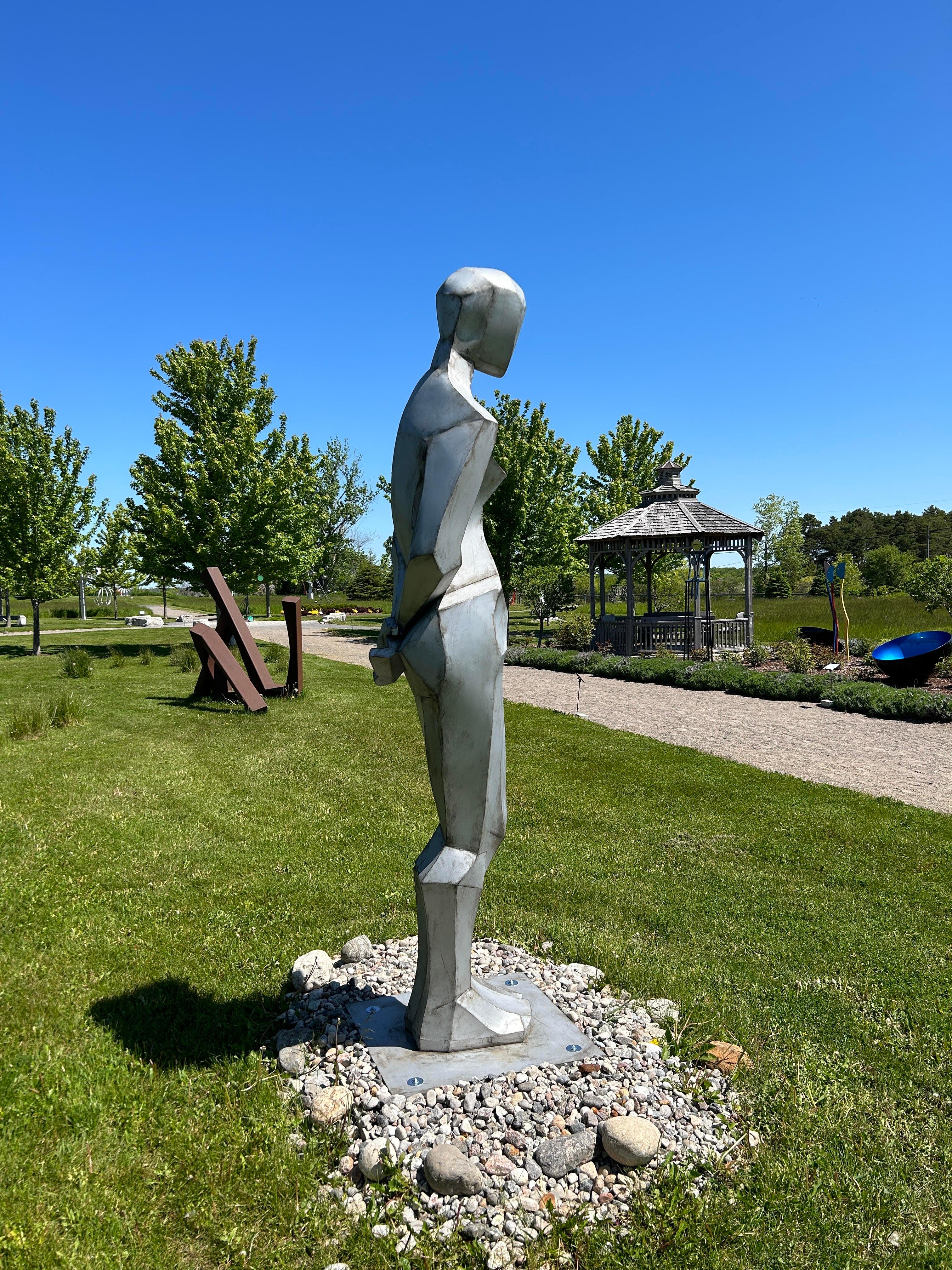 The striking angles of the female figure are captured in this abstract outdoor sculpture by Galina Stetco. The young Quebec based artist works as both a sculptor and a painter. This imposing piece created in stainless steel is of a woman standing,