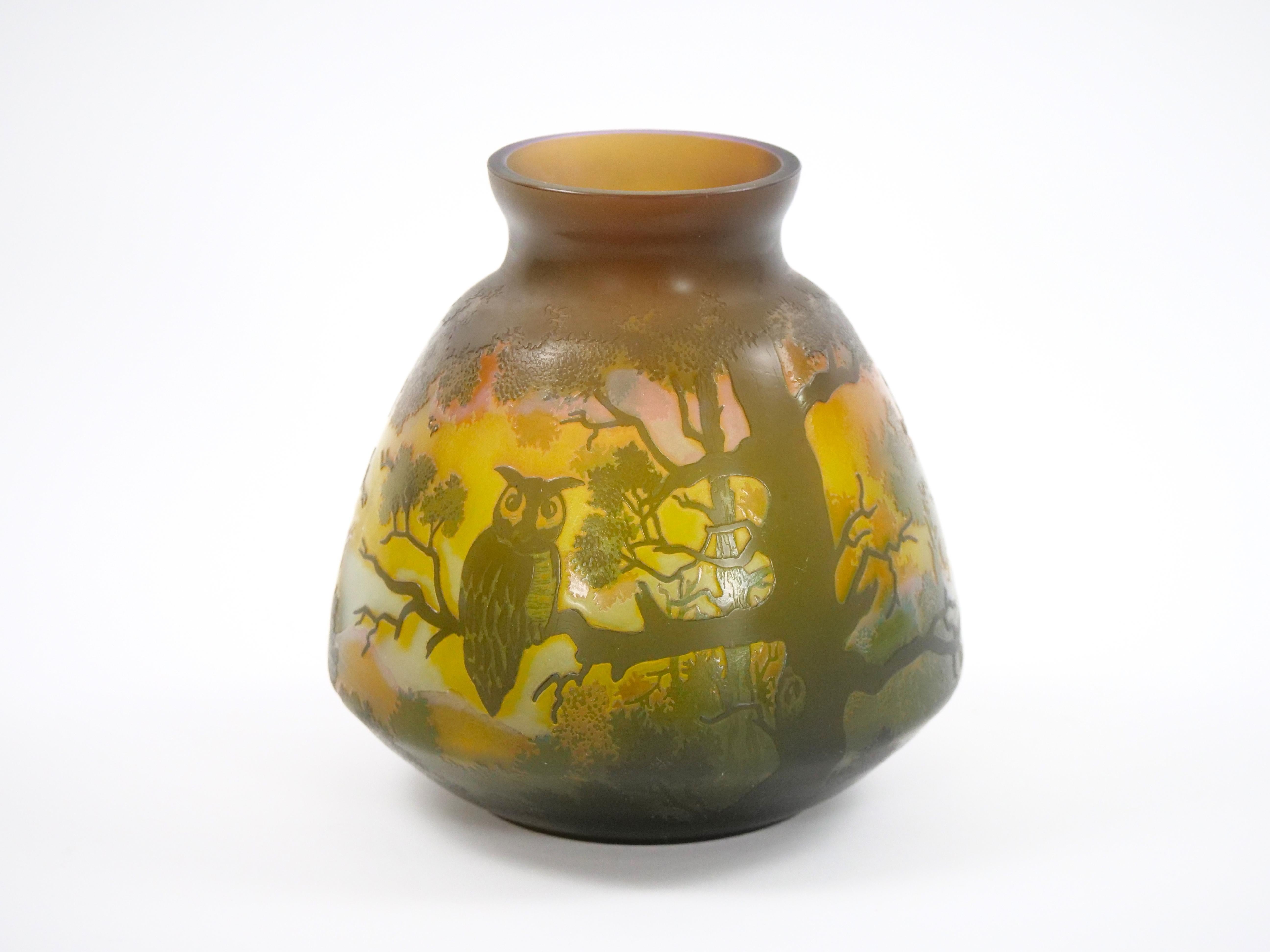 A beautiful cameo glass vase depicting perched owl birds in a forest with mountains in the distance.